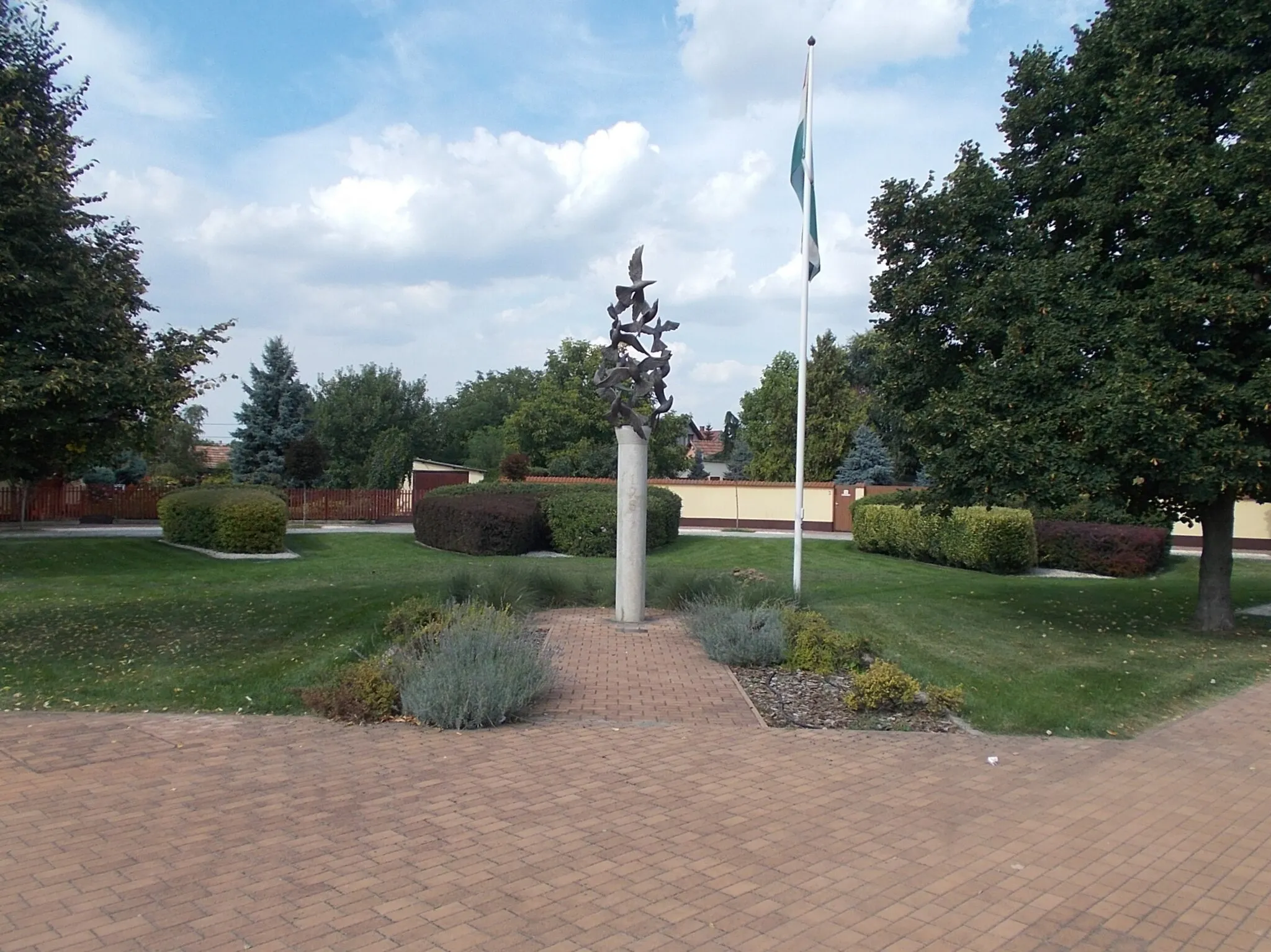 Photo showing: Memorial column of the 1956 Hungarian Revolution by Károly Barth (2006 works, 2.5-3 meters high limestone column, nine 'flying' bronze birds). There are ground based plaques at the memorial - in a Park at Szent István Street and Somogyi Béla Street intersection, /Szent István Square other name Templom Square/, Gyálliget neighborhood, Gyál, Pest County, Hungary.