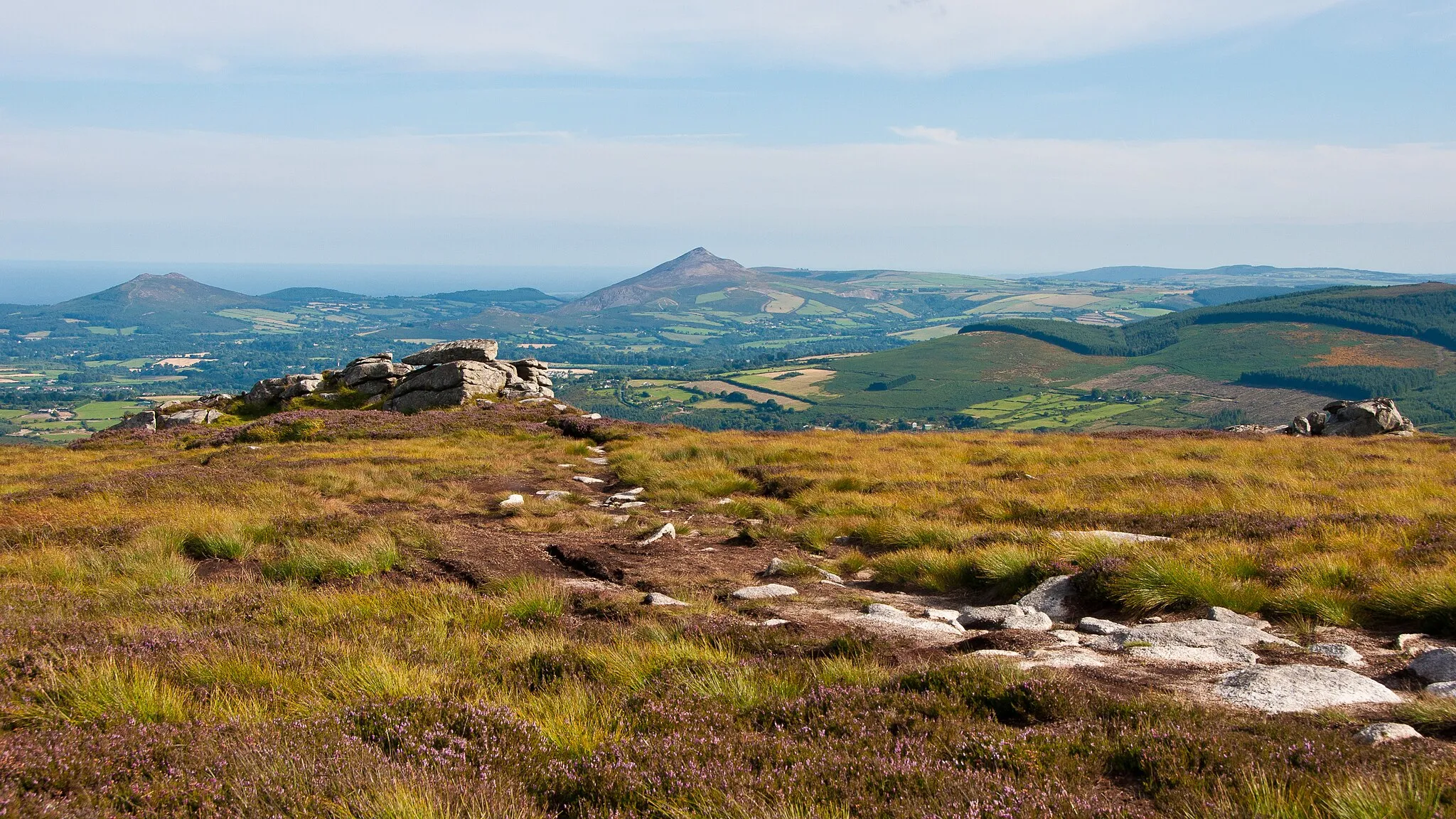 Photo showing: The twin tors (rock piles in foreground, left and right) give Two Rock mountain (foreground) in County Dublin in Ireland its name. The mountains in the background are Little Sugar Loaf mountain (left) and Great Sugar Loaf mountain (right), both in County Wicklow.