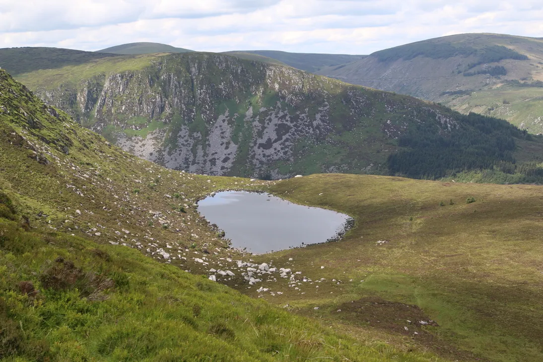 Photo showing: Arts Lough in Wicklow looking across the Fraughan Rock Glen to the summit and cliffs of Benleagh (Conavalla is the mountain in the background right