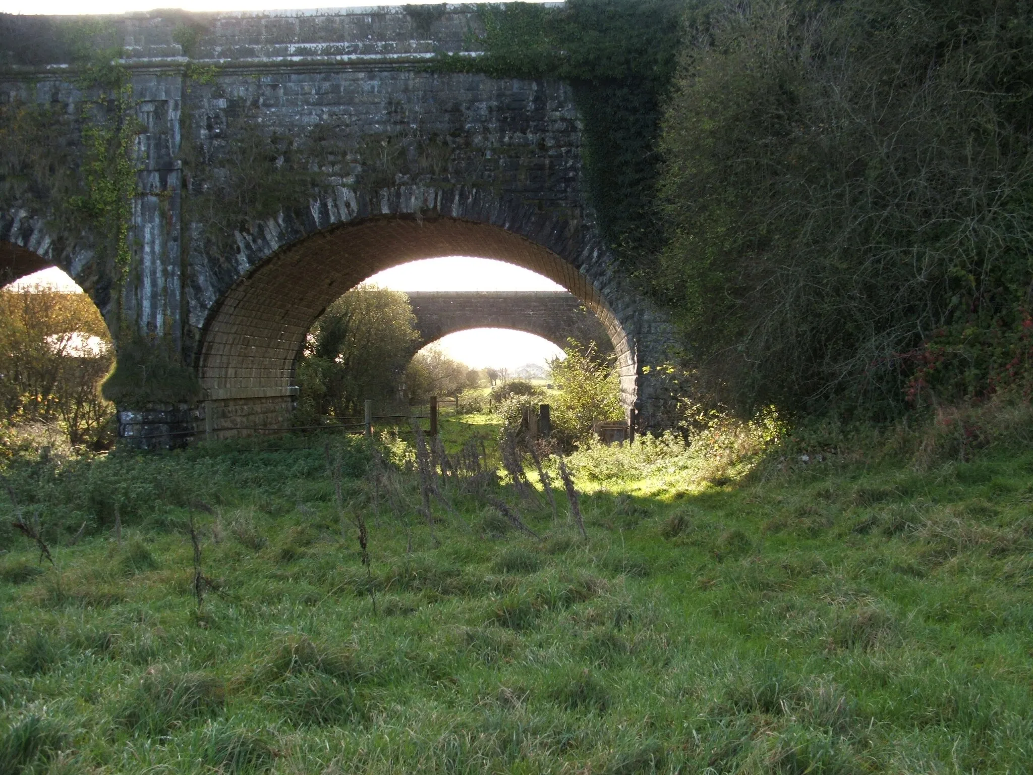 Photo showing: The canal passes over this aqueduct. Under the aqueduct passes the river Boyne. The second bridge in the background carries a railway line that runs parallel to the canal for many miles.