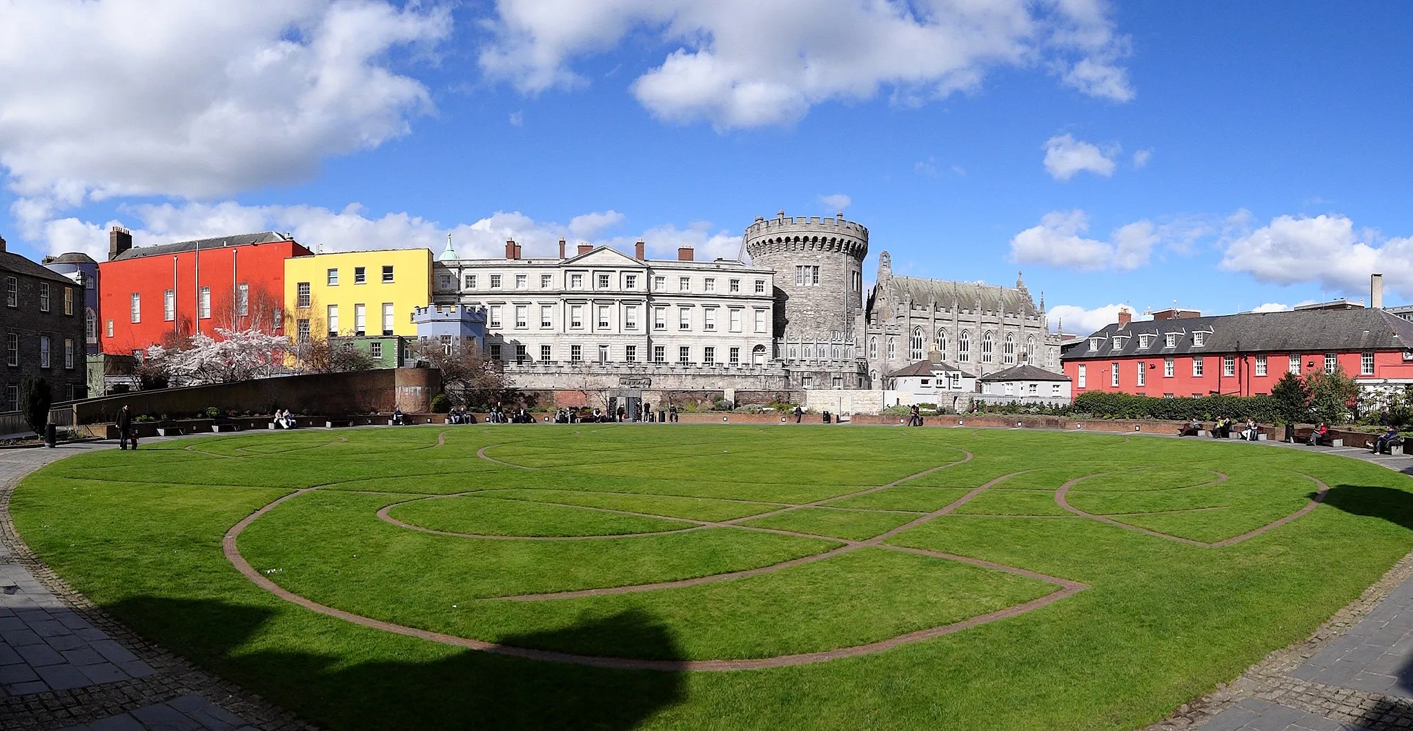 Photo showing: Dublin Castle seen from the "back side", a park surrounded by the Chester Beatty Library on the west side (barely showing in the left side of the photo), a police station on the east side (showing to the right, a light red building), and Dublin Castle on the north side. 
The bits of the castle shown here are, from left to right or west to east, (barely, the bluish tower partially covered by the library building) The Bermingham Tower, the red Saint Patrick's Hall, the yellow Battleaxe Landing, the bluish-grey Octagonal Tower, the State Apartments, the Record Tower (the tallest bit) and finally the Chapel Royal.