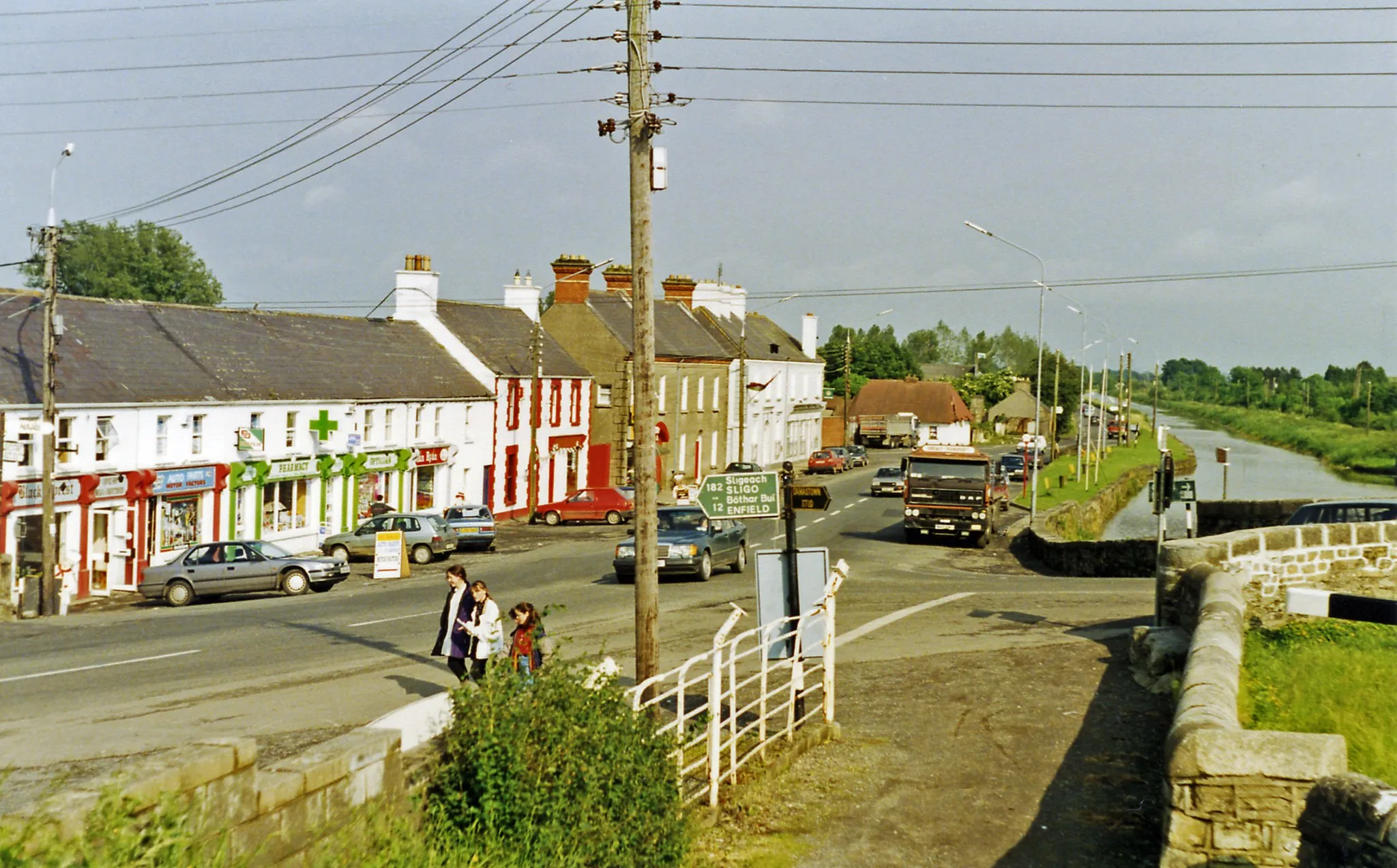 Photo showing: Leaving Kilcock on N4, the main road to Dublin.
View eastward, towards Maynooth and Dublin. On the right is the Royal Canal, which runs from the River Shannon at Termonberry, near Longford (Co. Westmeath) all the way to Dublin, and here forms the boundary between Cos. Meath and Kildare. (Note the lock-gate beams on the right). (This was before the M4 motorway was built).
