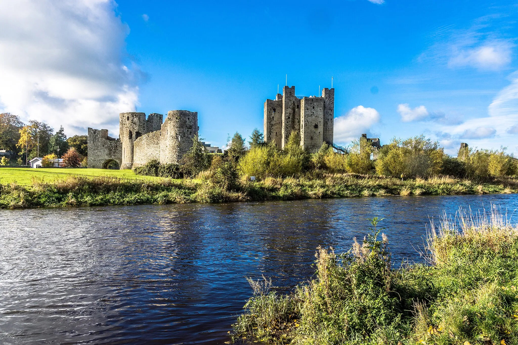 Photo showing: This weekend I had the good fortunate to visit the town of Trim in County Meath and the weather on Sunday morning was really beautiful so I decided to visit some of the many historic sites nearby.
With an area of 30,000 m², Trim Castle is the largest Cambro-Norman castle in Ireland. The design of the central three-story keep (also known as a donjon or great tower) is unique for a Norman keep being of cruciform shape, with twenty corners. It was built on the site of the pevious large ring work fortification in at least three stages, initially by Hugh de Lacy (c. 1174) and then in 1196 and 1201–5 by Walter de Lacy. Part of the interior of the castle was archaeologically excavated by David Sweetman of OPW in the 1970s and more extensively by Alan Hayden in the 1990s.
The surviving curtain walls are predominantly of three phases. The west and north sides of the enciente are defended by rectangular towers (including the Trim Gate) dating to the 1170s, the Dublin gate was erected in the 1190s or early part of the 13th century and the remaining wall to the south with its round towers dates to the first two decades of the 13th century. There are two main gates into the castle. The one in the west side dates to the 1170s and sits on top of s a demolished wooden gateway. The upper stories of the stone tower were altered to a semi-octagonal shape, c. 1200. A single round towered gate with an external barbican tower lies in the south wall and is known as the Dublin Gate. It dates from the 1190s or early 13th century and was the first of its type to be constructed in Ireland.

Apart from the keep, the main extant structures consist of the following: an early 14th century three towered fore work defending the keep entrance and including stables within it and which was accessed by a stone causeway crossing the partly filled-in ditch of the earlier ringwork; a huge late 13th-century three aisled great hall with an under croft beneath its east end opening via a water gate to the river; a stout defensive tower turned into a solar in the late 13th century at the northern angle of the castle; a smaller aisled hall added to the east end of the great hall in the 14th or 15th century; a building (possibly the mint) added to the east end of the latter hall; two 15th- or 16th-century stone buildings added inside the town gatehouse, 17th-century buildings added to the end of the hall range and to the north side of the keep and a series of lime kilns, one dating from the late 12th century the remainder from the 18th and 19th centuries.