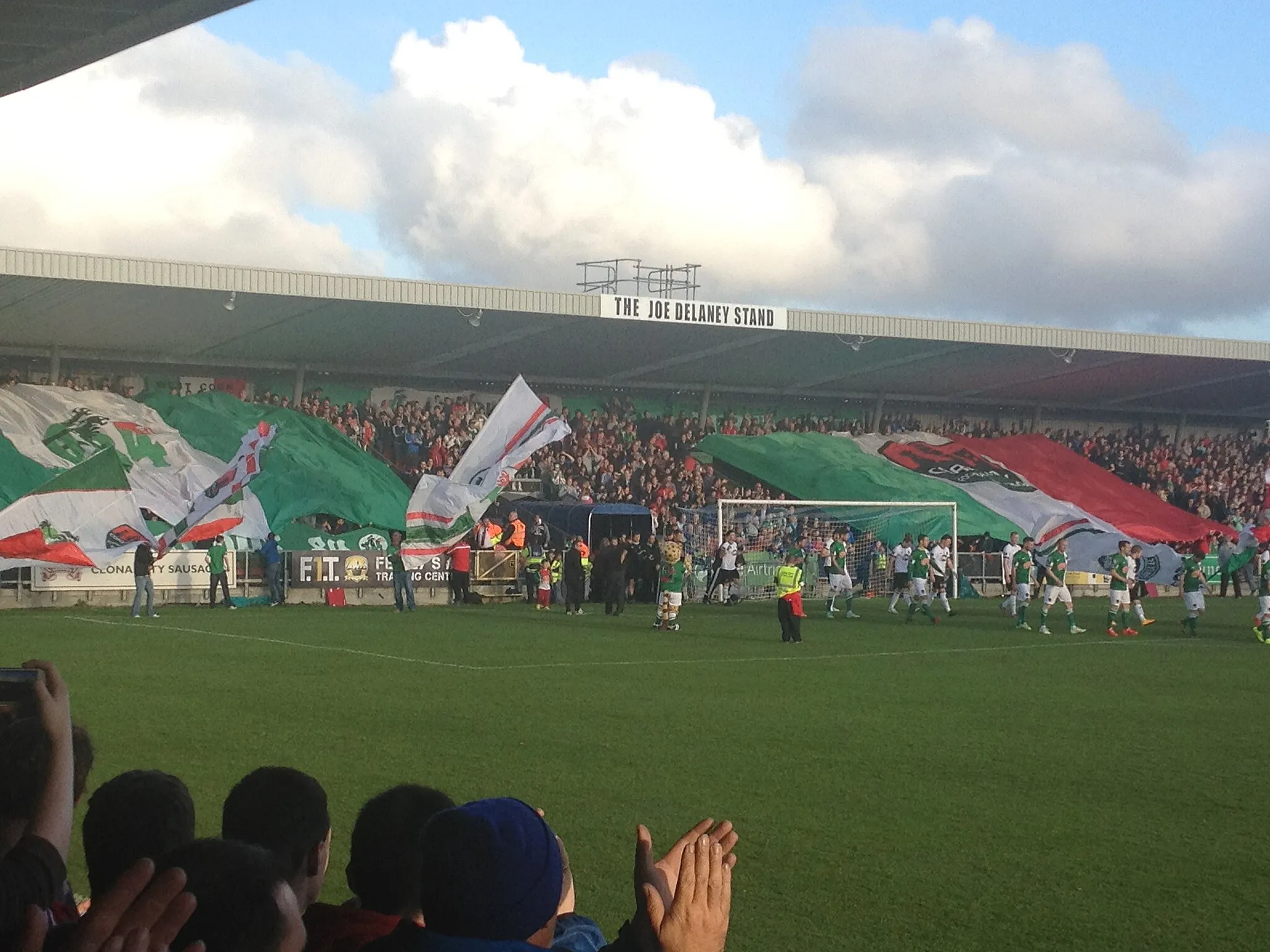 Photo showing: Turners Cross Stadium, Cork, Ireland. Cork City FC's "shed end" supporters display colours as Cork City and Dundalk FC players exit the tunnel. Image taken from Derrynane road stand, looking towards Curragh Road end ("shed end"). The match on 24 April 2015 was played on-front of 6,900 spectators and ended Dundalk 2 Cork City 1.