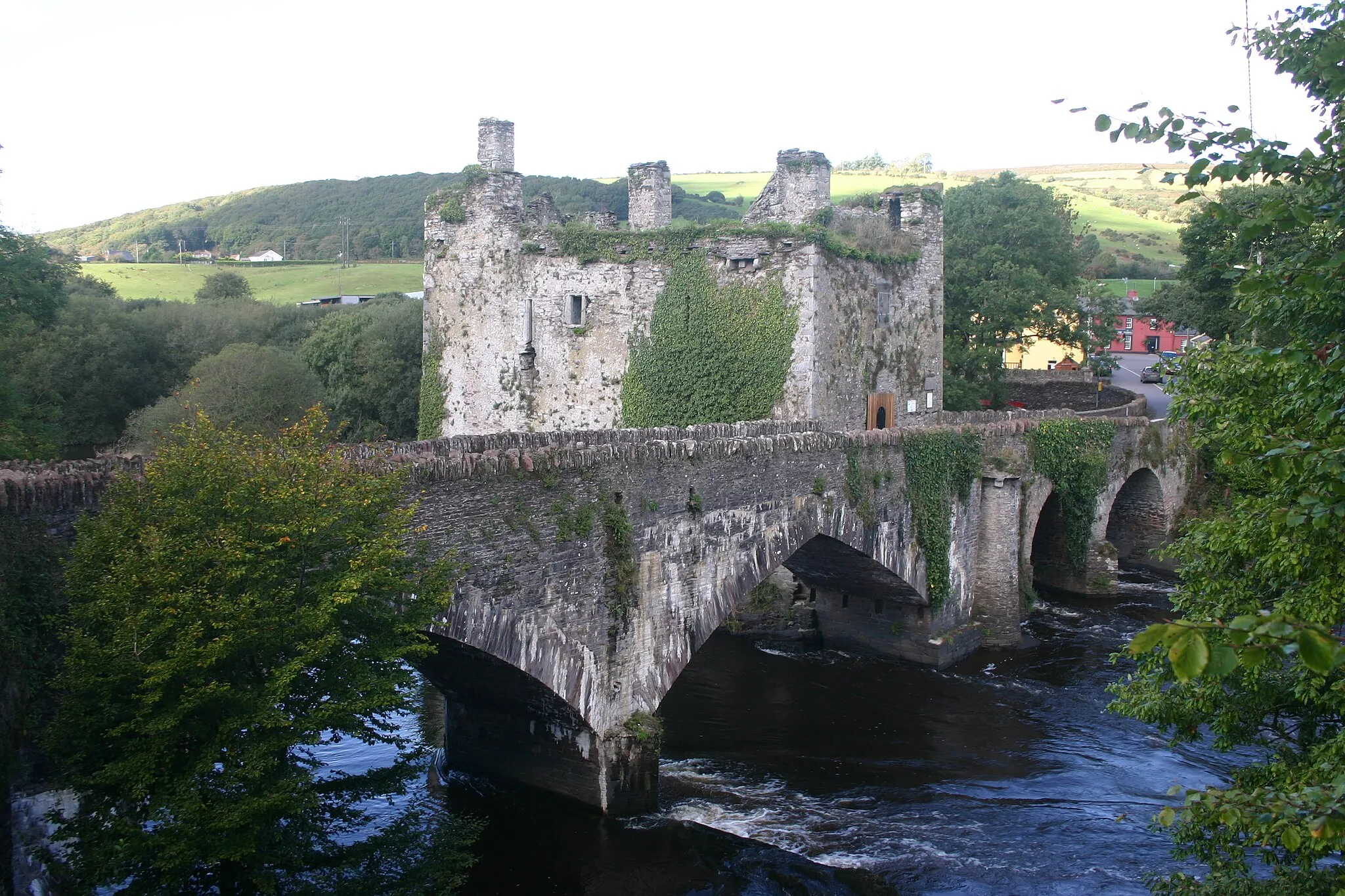 Photo showing: Carrigadrohid castle is a 15th century tower house overlooking an impressive stone bridge built in two parts- pointed arch to one side of the castle (19th century in date) and round arched to the other side of the castle (18th century in date).