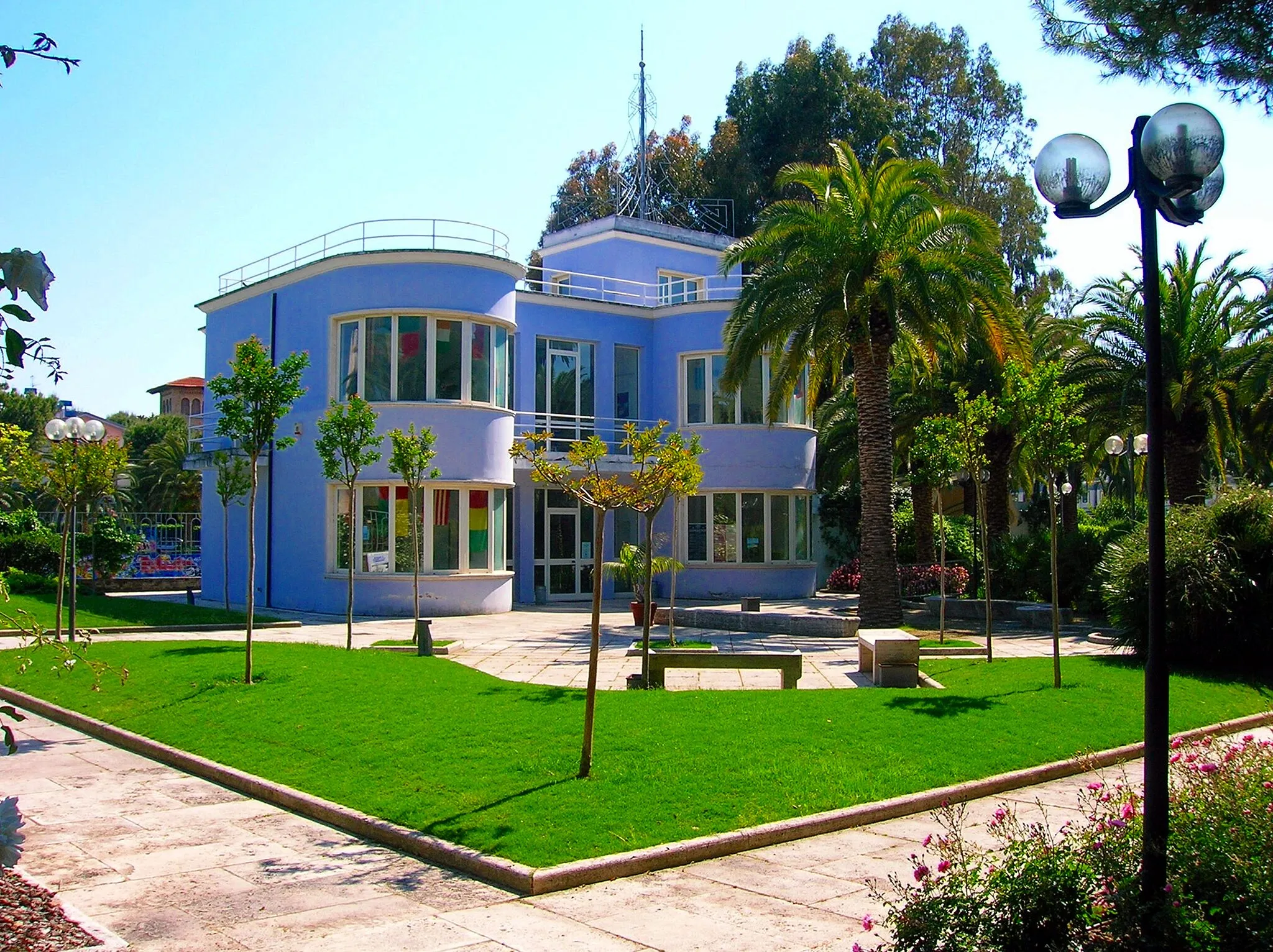 Photo showing: The Palazzina Azzurra was inaugurated on 1 September 1934. In a purely rationalistic style, typical of the fascist era, it was built next to the two tennis courts and the Circolo Forestieri.
The two-storey building, painted in blue, housed on the ground floor bars, lounges, showers and services for men and women. After a period of decline, the Municipality of San Benedetto brought the structure back to its citizenship in the most authentic sense, with spaces for the promotion and dissemination of art, with exhibition rooms, offices and services, all completed by a park.