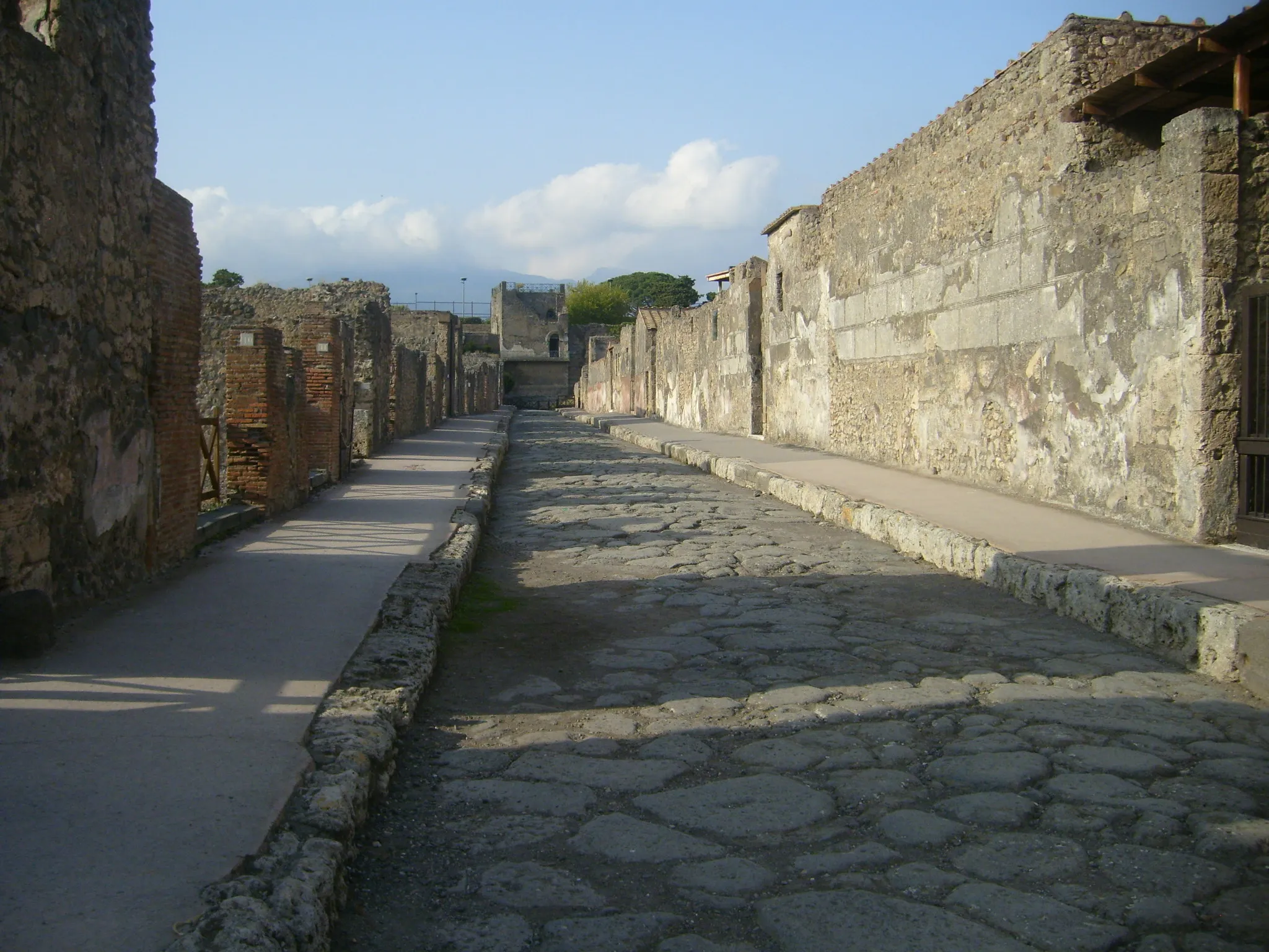 Photo showing: Via di Mercurio (Pompeii, looking northward from junction with Vicolo di Mercurio, towards Insula 9 of Regio VI (VI.9, right) and Torre XI in background.