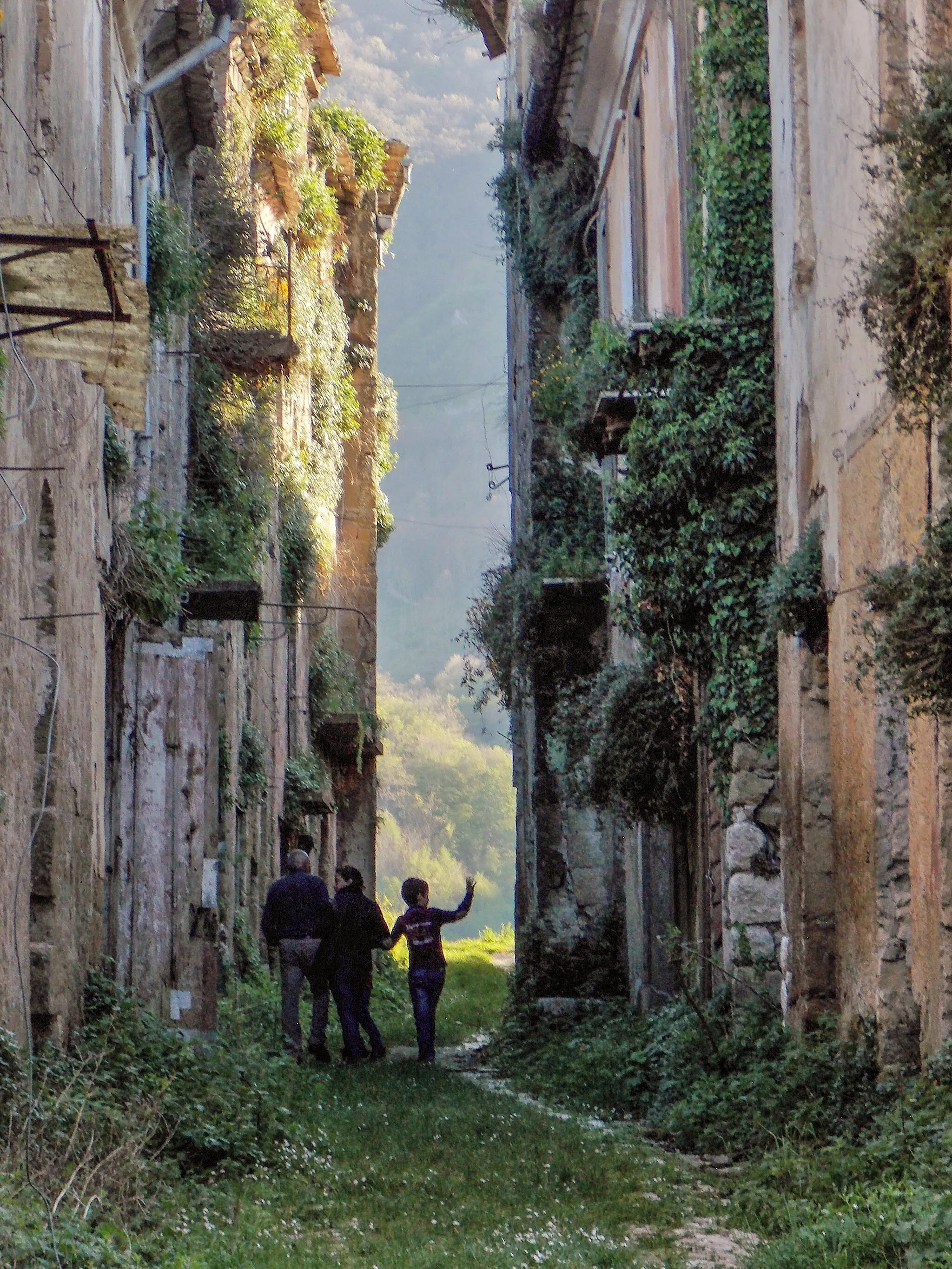 Photo showing: Tocco Caudio, Province of Benevento, Italy. The older settlement is likely to date from the age of Langobard domination over Southern Italy, and was severely damaged by two earthquakes in 1962 and 1980, respectively; the village was thus abandoned, and rebuilt in a different location. In this picture a local family is visiting the ruins along the old main village street.