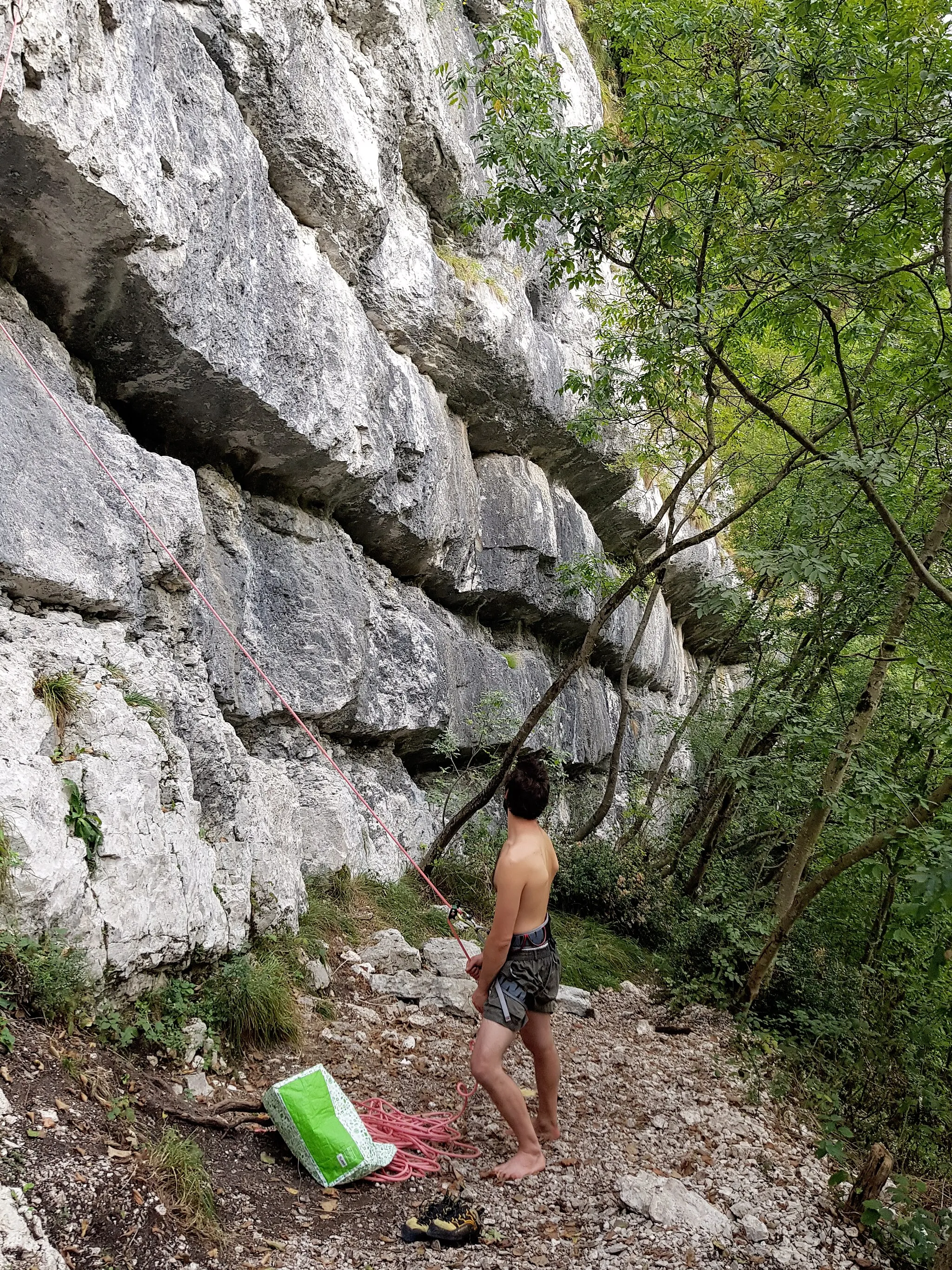 Photo showing: Picture of a shirtless belayer at the rock climbing crag "Raffaele Carlesso" of Dardago. The crag is named after Raffaele Carlesso, an alpinist climber and mountaneer born in Costa di Rovigo in 1908 that died in Pordenone in 2000. Dardago is located in the municipality of Budoia, province of Pordenone, region Friuli-Venezia-Giulia in Italy. Picture taken on the 29th of september in 2021.  2021-09-29