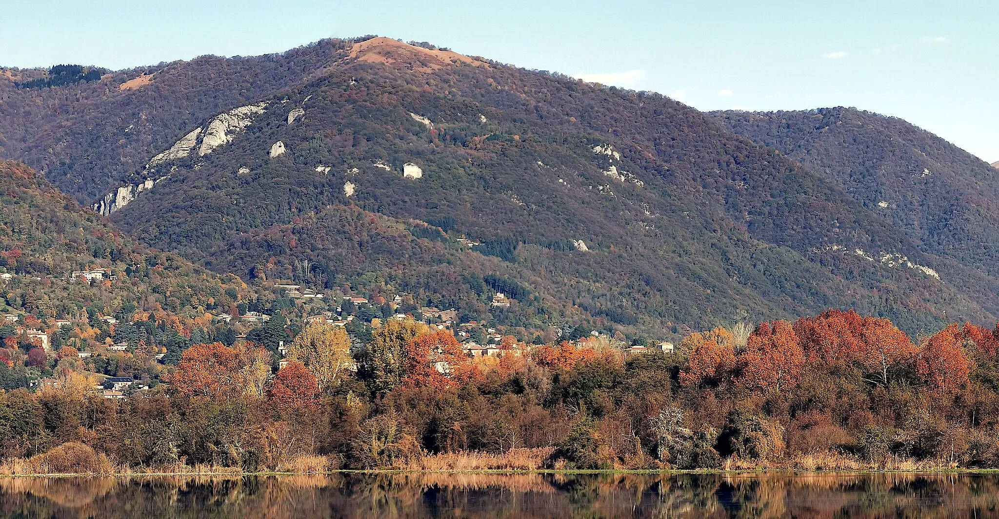 Photo showing: Il Monte Puscio visto dalla riva del Lago di Alserio. Lungo il crinale del monte, si individua la cima e (poco al di sotto) la croce del Monte Panigas.