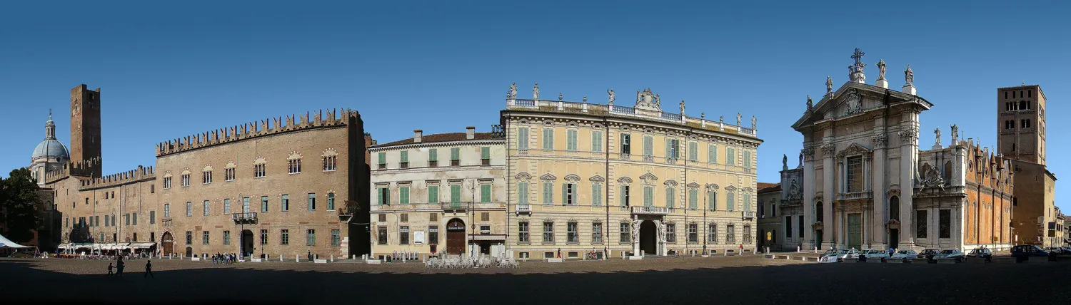 Photo showing: Piazza Sordello, Mantua, Lombardy, Italy. The west side of the Piazza features from right to left: the Duomo, the Palazzo Bianchi (yellow building), the Palazzo Bonacolsi (brown building);
in the background on the left is the Basilica di Sant'Andrea situated in the Piazza Mantegna.