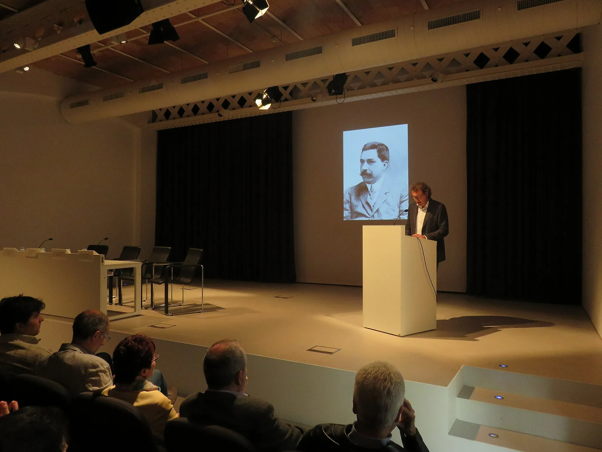 Photo showing: Acte de nomenament a títol pòstum de Joan Miquel i Avellí com a Fill Predilecte de la Vila de Palafrugell, el diumenge 19 d'abril de 2015, a l'auditori del Museu del Suro. Parla Xavier Rocas, historiador i regidor de cultura