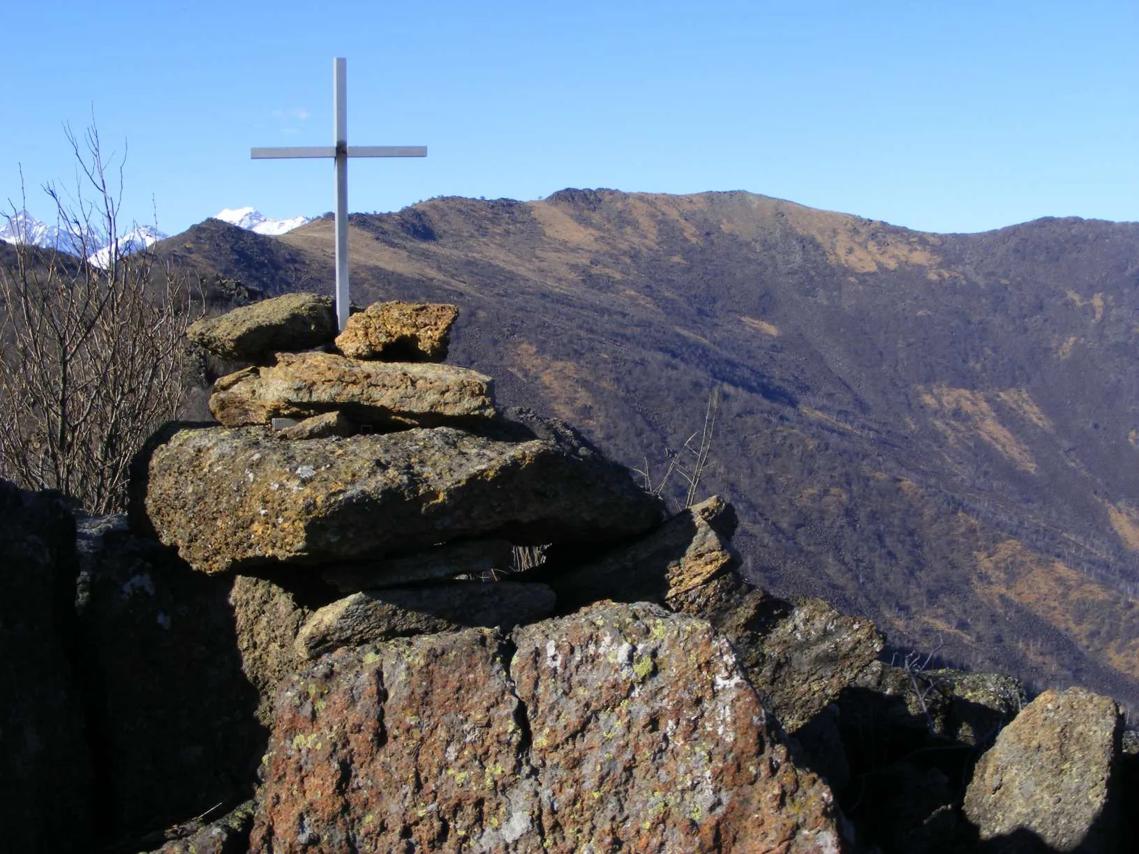 Photo showing: La piccola croce di vetta del Monte Lera (1.368 m); sullo sfondo il Monte Colombano