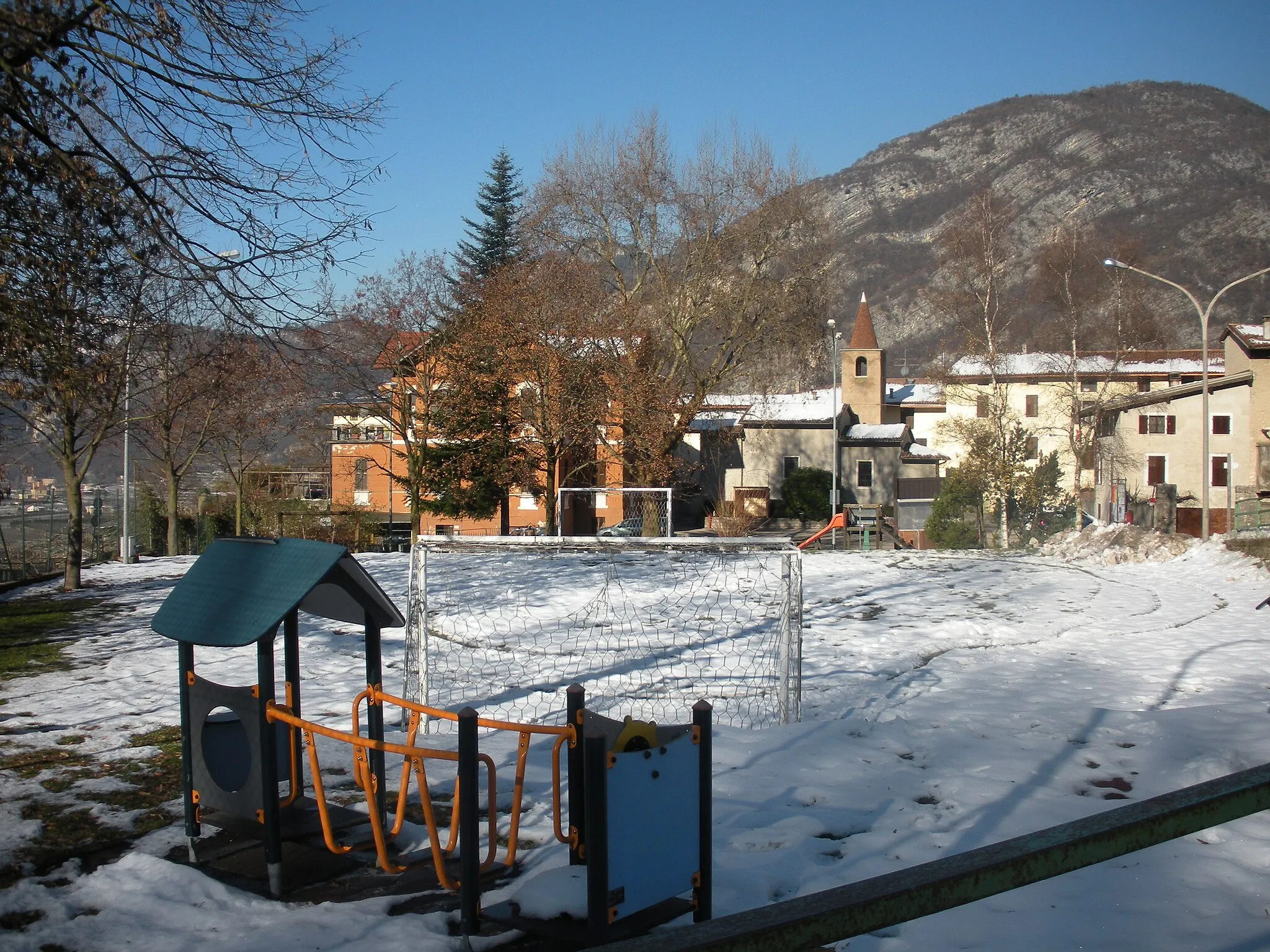 Photo showing: Si può vedere il parcogiochi con la neve, la piazza, la chiesa e varie case.