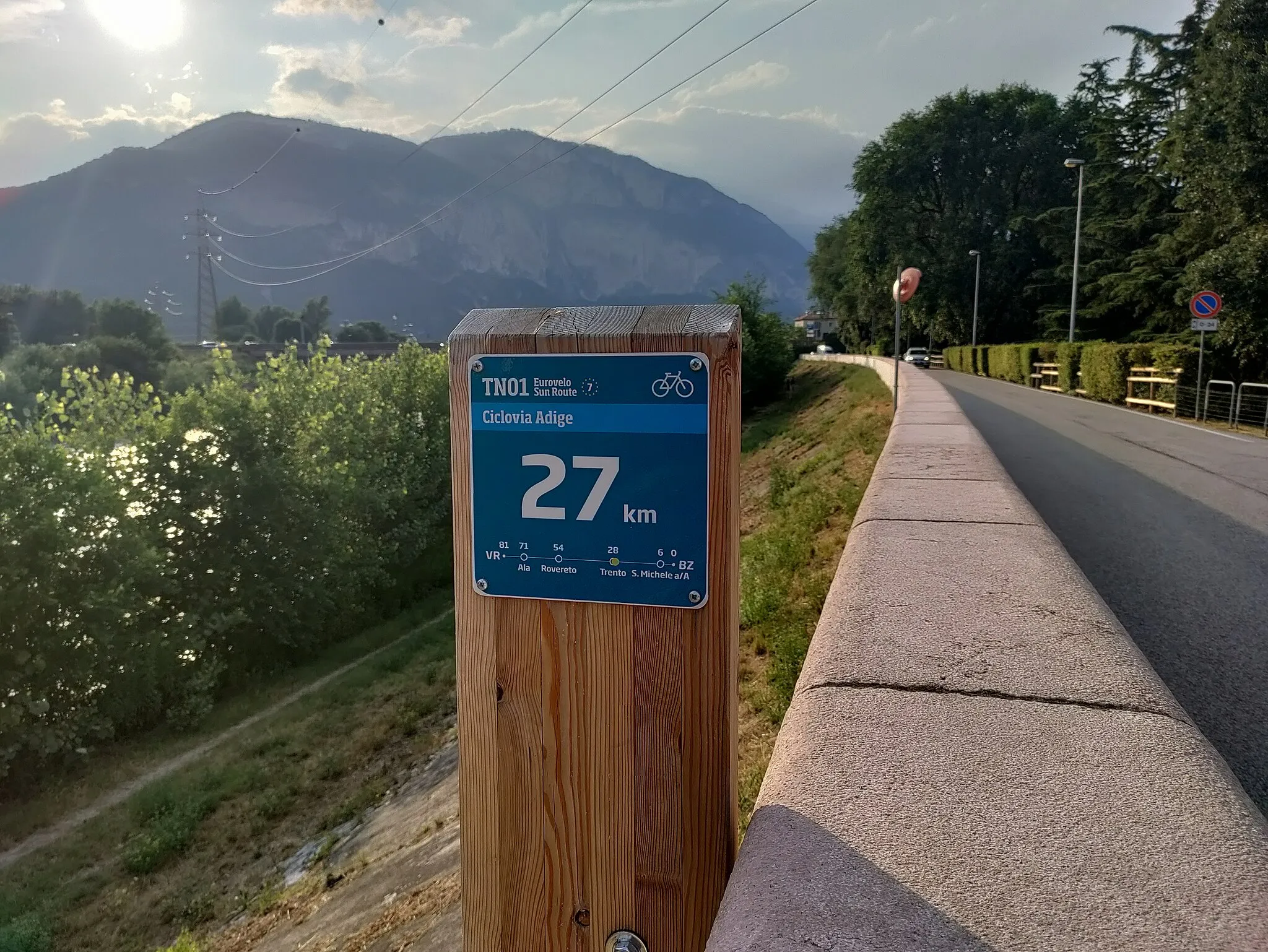 Photo showing: All cycle routes in the Province of Trento have mileage markers with reference to the main cities they go through. This one is positioned along river Adige, north of Ponte San Giorgio. Note also the indication of EuroVelo 7 itinerary, added with the last update in year 2023.