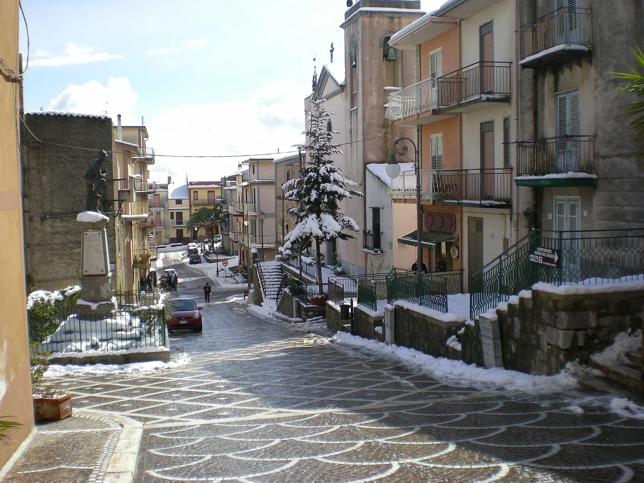 Photo showing: La via Roccaforte, il monumento ai caduti e la Chiesa innevati