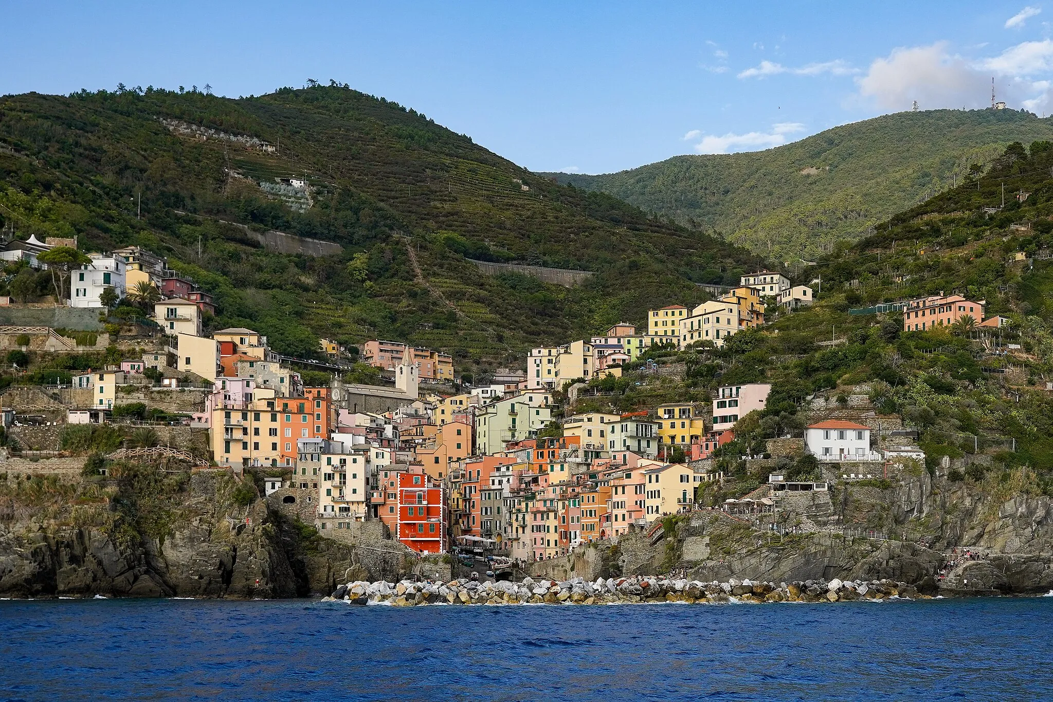 Photo showing: Riomaggiore village and harbour, view from the approaching ferry.  Mountain range about 650–750 m (2,130–2,460 ft) elevation. Cinque Terre, Liguria, Italy