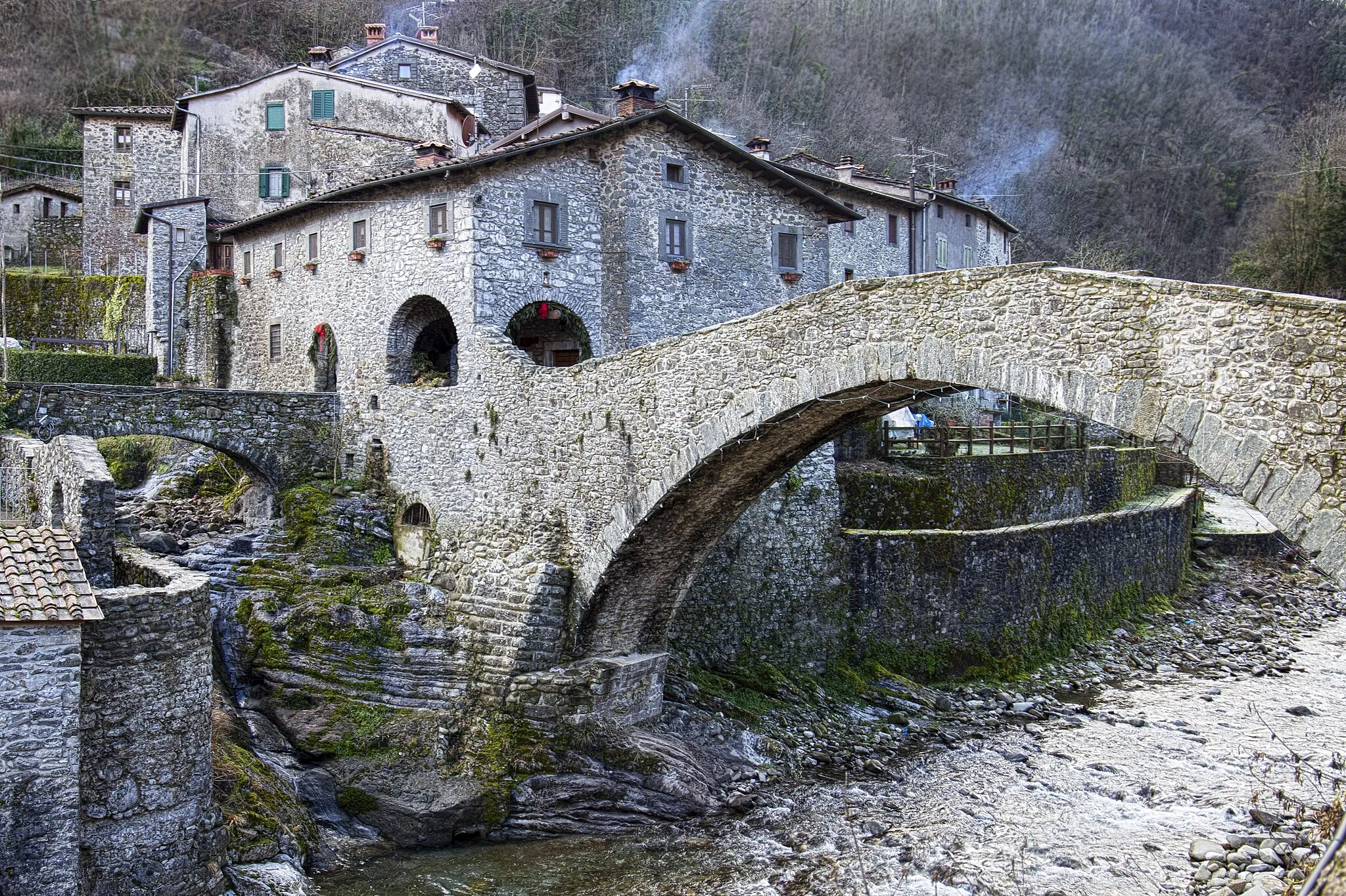 Photo showing: Il Ponte della Dogana non è un monumento molto conosciuto, bensì uno dei piccoli tesori della Toscana ancora escluso dalle rotte del turismo, si trova a Fabbriche di Vallico, provincia di Lucca.
Ponte pedonale che unisce le due parti del borgo, dove sotto scorre il torrente Turrite Cava. Questa struttura è molto importante poiché qui storicamente passava la linea di confine tra il territorio della Repubblica di Lucca e il Ducato Estense