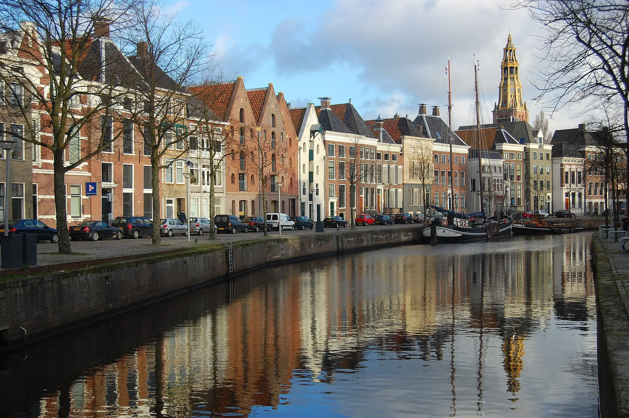 Photo showing: Old warehouses along the Hoge der Aa canal in the city of Groningen, the Netherlands. In the background, the tower of the A-kerk (A-church) can be seen