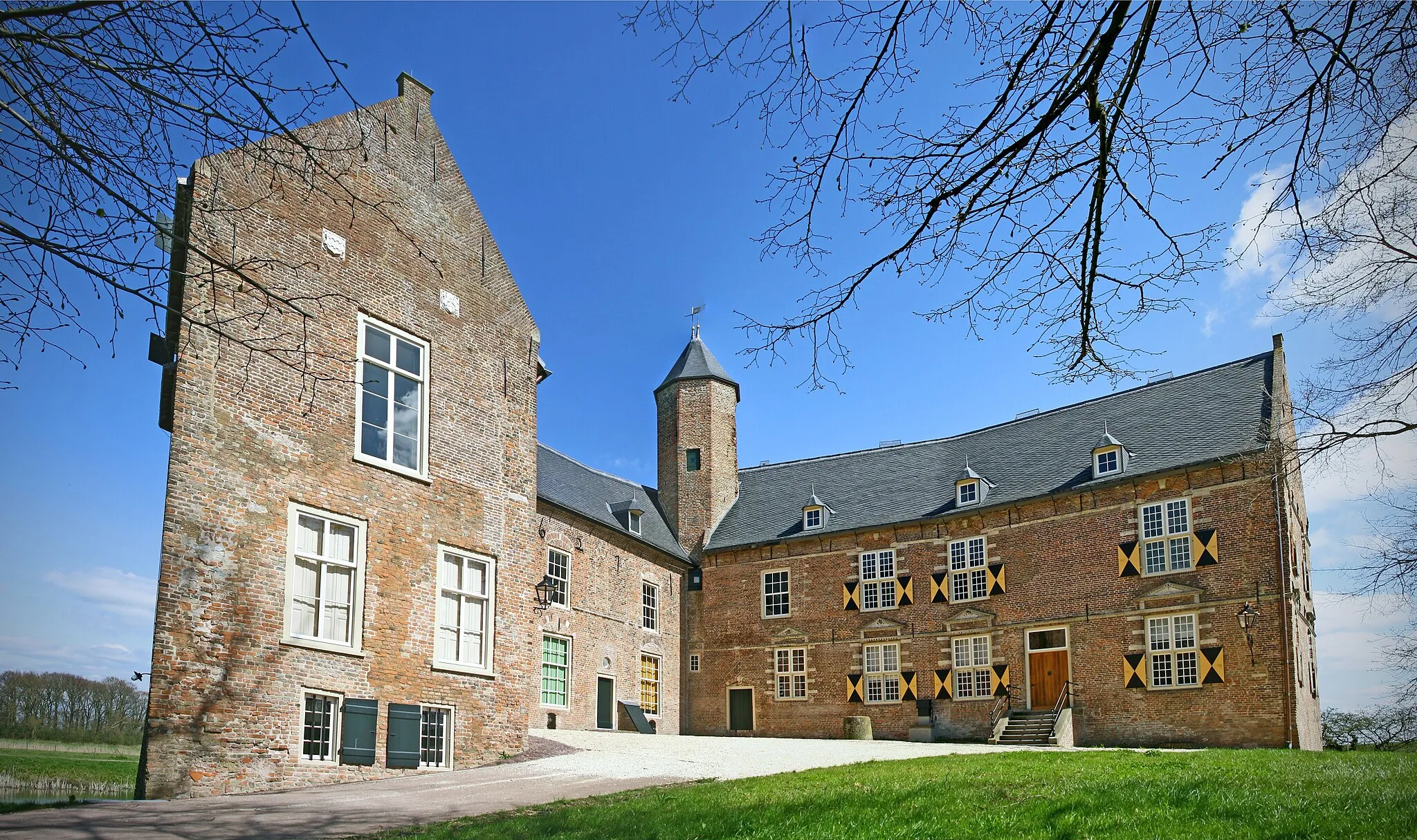 Photo showing: Waardenburg Castle nowadays is a remnant of a castle with a polygonal shape dating back to around 1283.
The castle was preceded by a wooden castle built in 1265. It was then known as Hiern Castle, named after the hill is was built on. This wooden castle was founded by a Rudolf Cock. His ancestors owned the castle until 1401, which was then known as Weerdenbergh Castle. This name translates as "washland hill".
During the Eighty Years War, in the 16th century, the castle was taken by surprise and pillaged. The castle was heavily damaged in the process; only its heavy walls and the shells of the towers survived. The castle remained a ruin until 1627 when a Johan Vijgh gained ownership and started partially rebuilding the castle. During this rebuilding the bailey and the southwing, in which the entrance gate was situated, were completely demolished.
In the following centuries the castle was successively owned by the Aylva and Van Pallandt families.
Even in 1895 the eastern wing of the castle was enlarged and fitted with a little stairtower.

Today the castle lies separated from the river Waal by a dike. But in earlier centuries the river flowed by its walls. Waardenburg Castle is now owned by the "Friends of the Castles of Gelderland"-foundation.