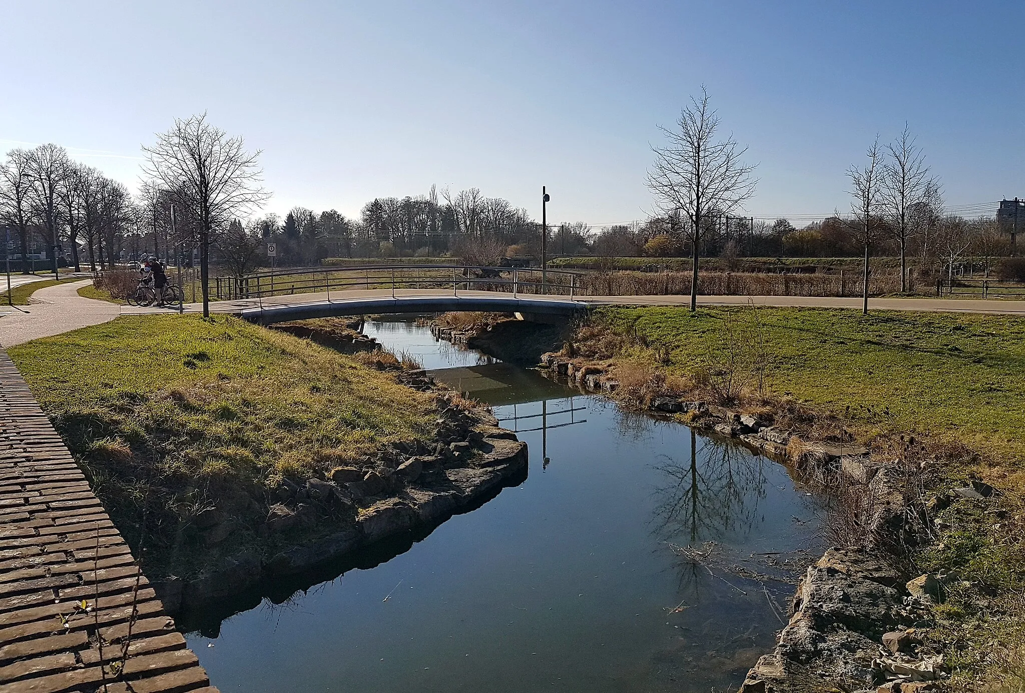 Photo showing: A pedestrian and bicycle bridge over the Kanjel brook opposite villa La Grande Suisse (or: Villa Kanjel) in Maastricht-Mariënwaard, Netherlands. The bridge is part of a new route for slow traffic called the Groene Loper ("Green Carpet"), connecting the south-east of Maastricht to the north-east.