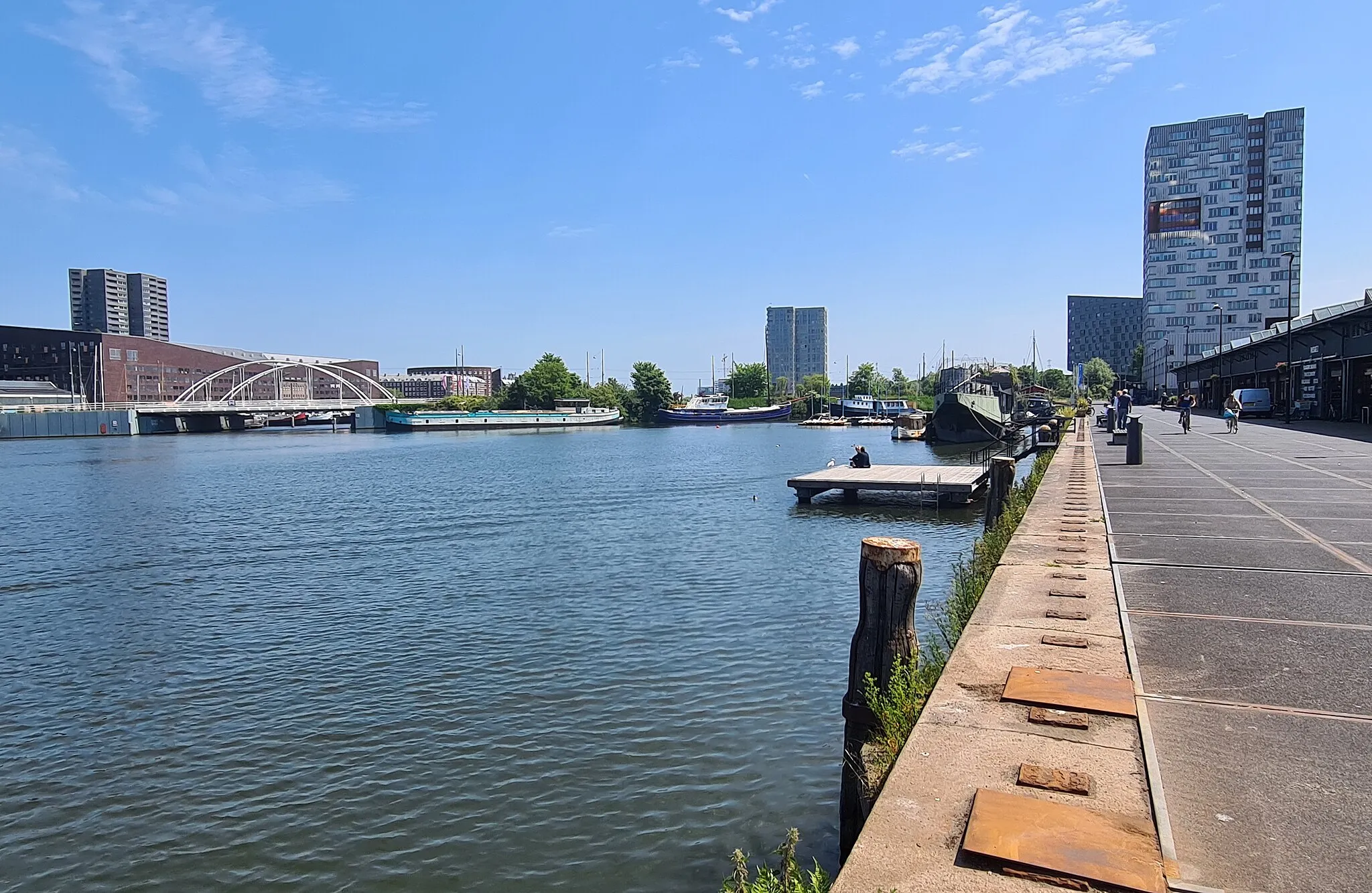 Photo showing: Gezicht naar het oosten op de Veemkade en de IJhaven in het Oostelijk Havengebied in Amsterdam. Op de achtergrond de Verbindingsdam, bebouwing op het KNSM-eiland, en de woontorens Steltloper en IJ-toren.