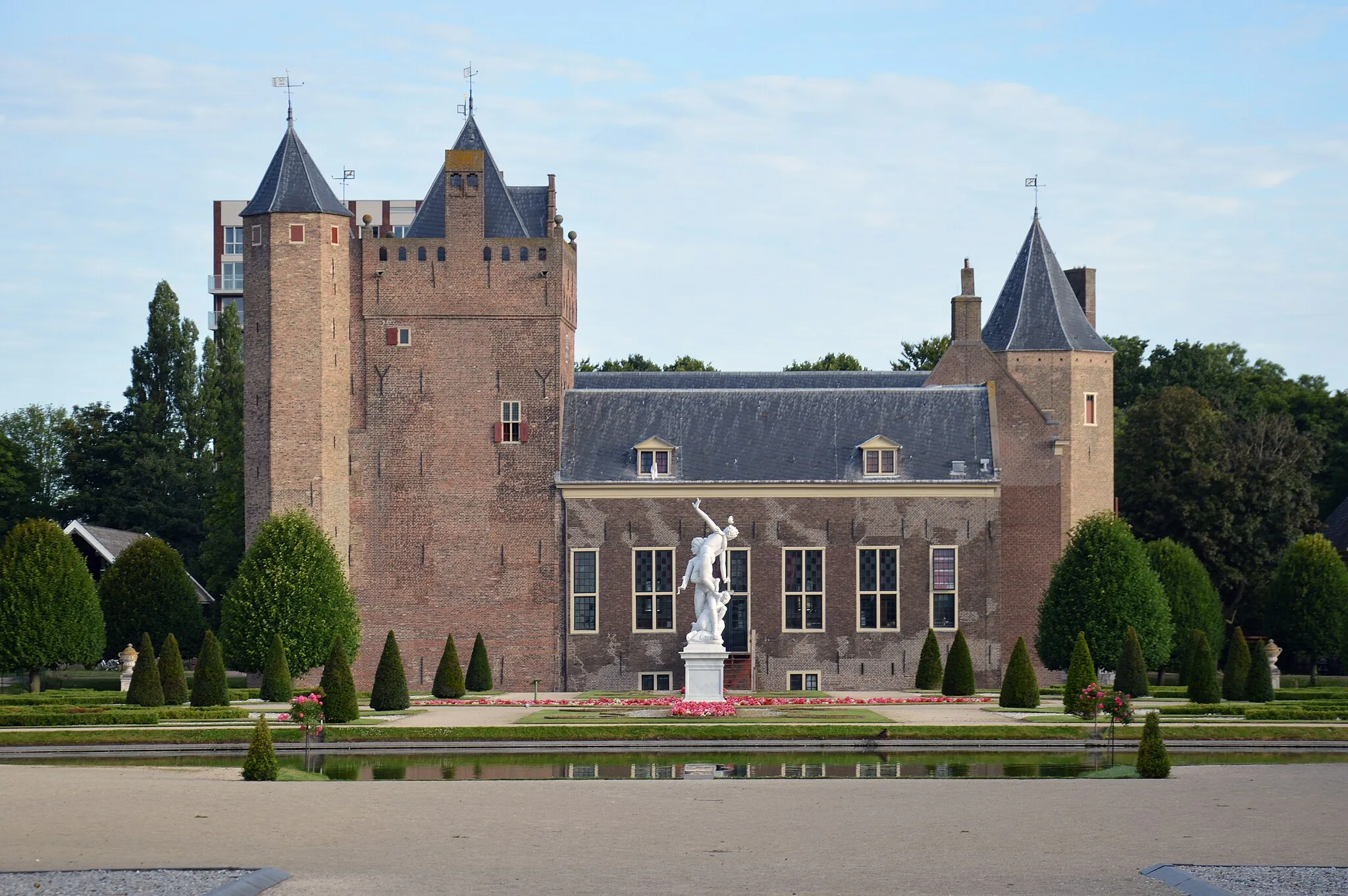 Photo showing: Garden view of the southeast (rear) façade of Assumburg Castle, Heemskerk, on a summer's morning in 2022. In the foreground is part of the French classicist garden and the sculpture Sabijns Poppenspel by Dutch sculptor Elisabet Stienstra (2012).