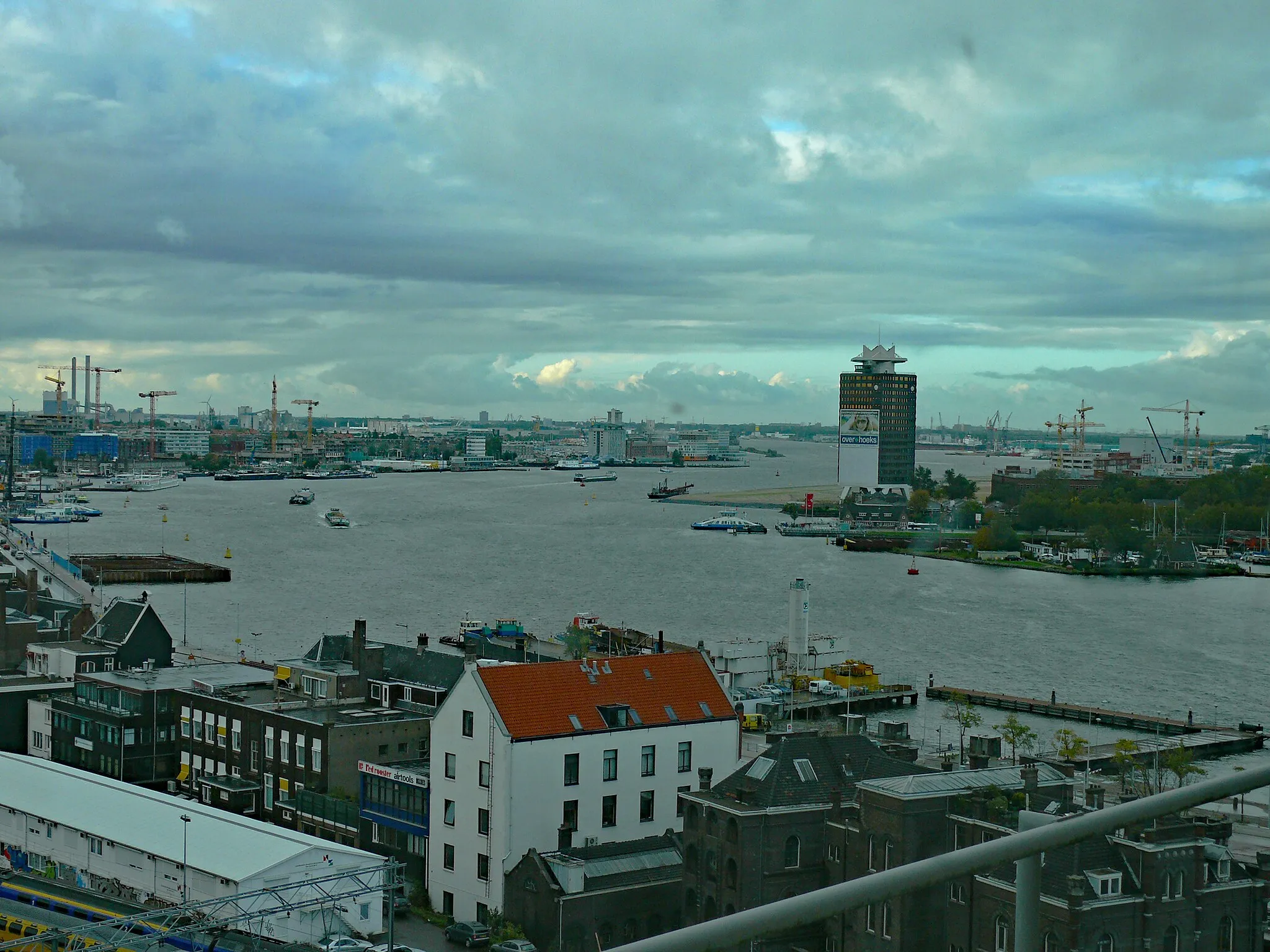 Photo showing: (Amsterdam photo, 2006) - a view over the curving river IJ, seen from Oosterdokseiland. On the right side the North border of the river IJ with the Shell tower. A ferry is just crossing the water. City Photography of The Netherlands, Fons Heijnsbroek; free photo CCO in high resolution.