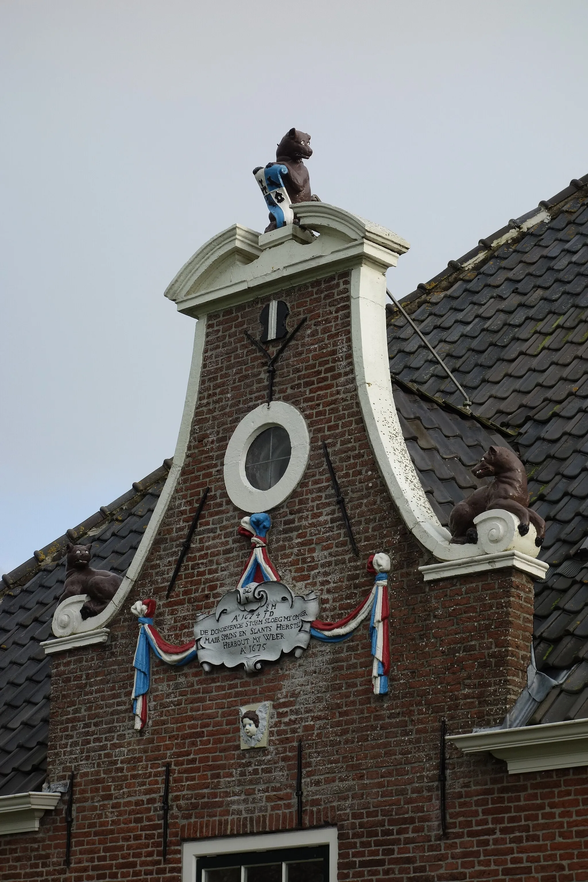 Photo showing: Dakkapel van de stolpboerderij Zandwerven 45 in Spanbroek. De gemetselde dakkepael bevat een gebroken fronton met daarin een wolf met wapenschild. Op de hoeken liggen twee wolven. In plaats van een groot raam hangt er een festoen met daaraan een gevelsteen. Onder de gevelsteen een gevleugeld engelenkopje.