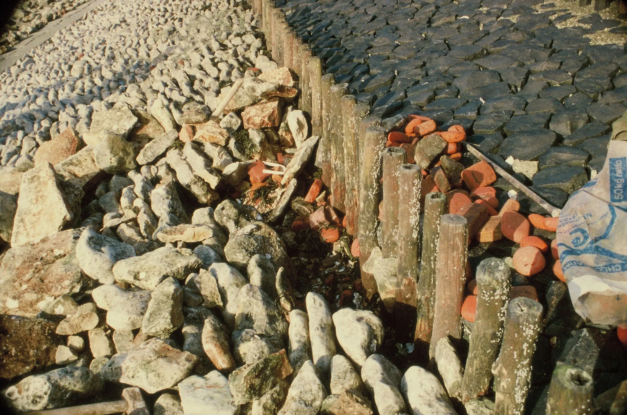 Photo showing: Zeedijk bij Strijenham, Tholen. Schade aan een glooiing van Vilvoordse steen; daarboven een palenrij als scheiding tussen de steensoorten. Onder de Vilvoordse steen was een vlijlaag van baksteenpuin aangebracht.