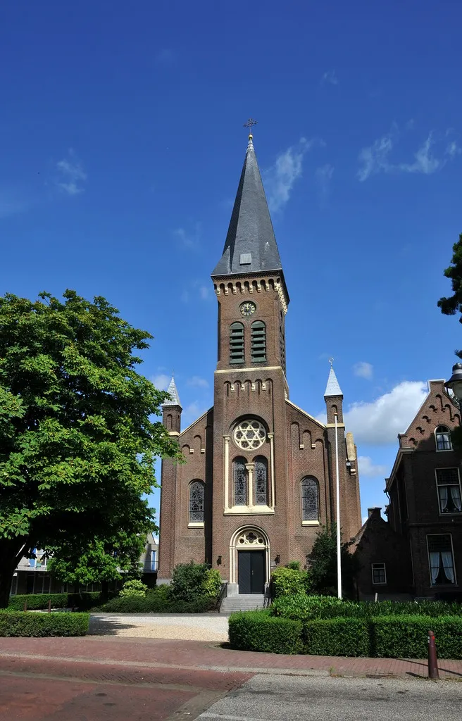 Photo showing: De kerk werd gebouwd op de plaats van een kerk uit 1845 van Theo Molkenboer, die al na twee decennia vervallen bleek te zijn. De architect van de nieuwe kerk was Herman Jan van den Brink. Hij ontwierp een eenbeukige kerk in neoromaanse stijl, met boven de ingang een half-ingebouwde toren en 2 arkeltorens daarnaast. De kerk werd met kerstmis 1868 in gebruik genomen. De 5 gebrandschilderde koorramen zijn ontworpen door J.B Capronnier. Binnen staat een orgel van de firma Maarschalkerweerd te Utrecht.
Bron: Wikipedia