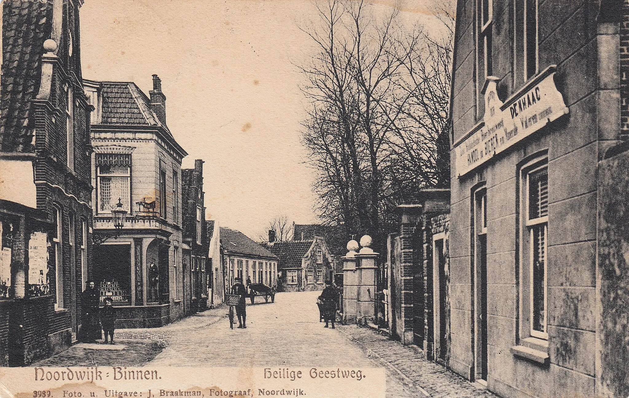 Photo showing: Heilige Geestweg, oude prentbriefkaart uit 1907, Noordwijk-Binnen. Links op de foto het voormalige raadhuis van Noordwijk (tot 1887), het pand is hier nog in die staat, maar werd in 1927 verbouwd door de fa. Baalbergen die de nieuwe eigenaar was. Om de hoek van het pand is de ingang van de Kerkstraat. Deze foto is tussen de twee kerken in. Rechts achter de bomen is de Oude- of St. Jeroenskerk. Een muur en ingang van het terrein (een poort) zijn op deze prent te zien.