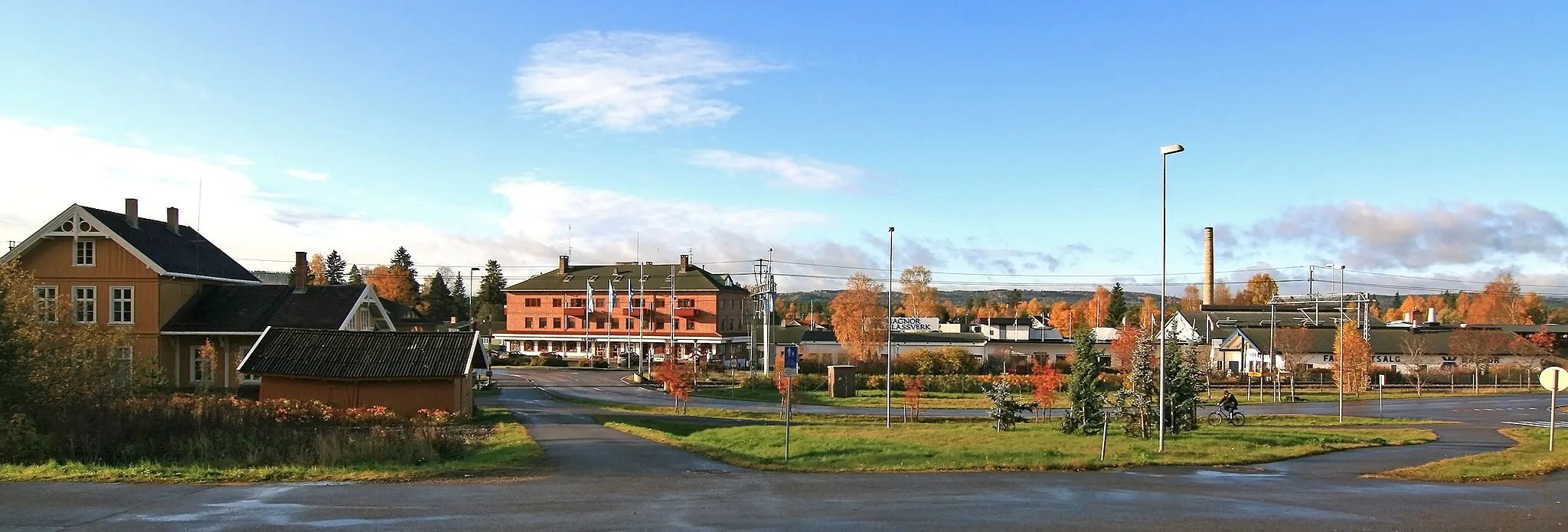 Photo showing: Magnor, Eidskog, Hedmark. Jernbanestasjonen til venstre og Magnor Glassverk til høyre.