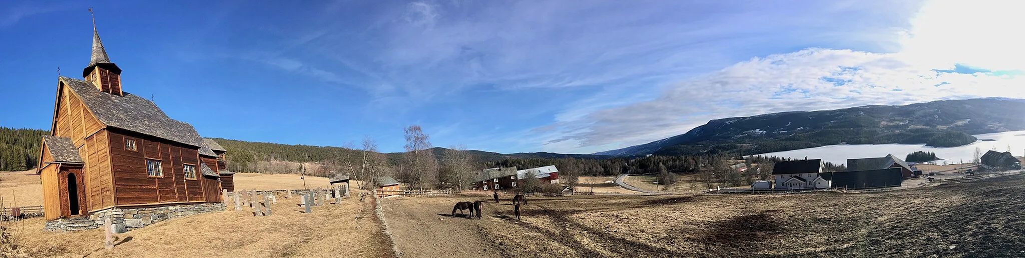 Photo showing: Lomen Stave Church (Lomen stavkyrkje/stavkrike) in Vestre Slidre Municipality in County of Oppland, Norway. Horses on field. View towards Slidrefjorden. Distorted panorama photo March 29th, 2017.
Through dendrochronological dating this small church in the traditional region of Valdres has been dated to 1192, but the first reference in written sources is not until 1325 and 1334, at that time as "Hvams kirke". The church was rebuilt and enlarged in 1749.