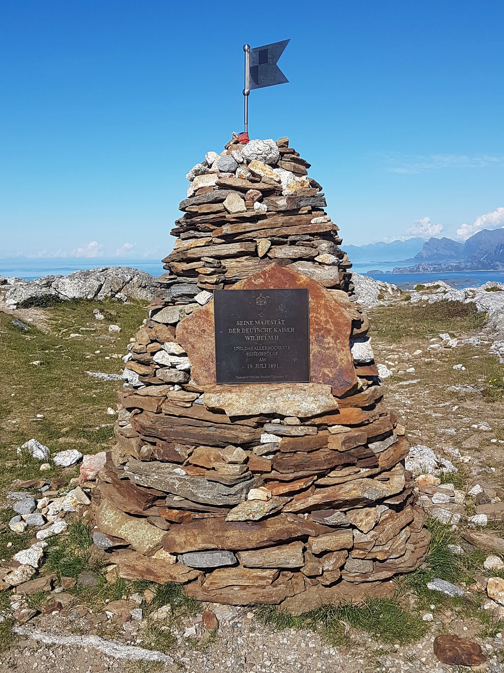 Photo showing: Guidepost on Keiservarden. In the background a ship of Hurtigruten line infront of Landegode island, at the horizon silhouette of Lofoten mountains can be seen.