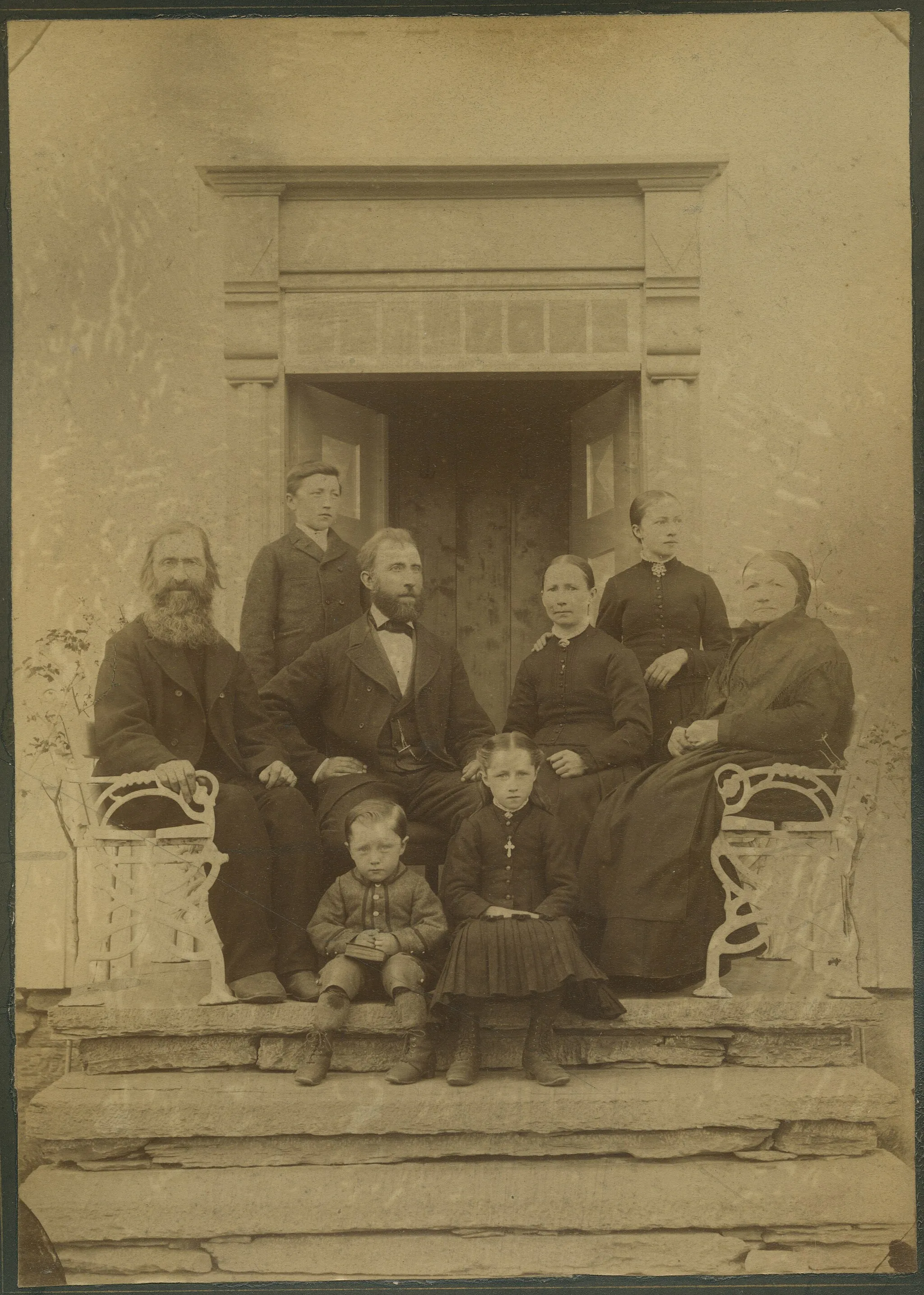 Photo showing: Søren og Mette Fiskvik med familie, fotografert 16.07.1888 på trappa på deres eiendom Ragnheim på Skatval. Foran fra venstre sitter deres barn Ragnar Fiskvik (f. 1885) og Johanne Fiskvik (f. 1879). Sittende fra venstre: Rasmus Sørensen Fiskvik (f. 1814, Sørens far), Søren Fiskvik (f. 1844), Mette (Hammer) Fiskvik (f. 1848) og Ingeborganna Persdatter Fiskvik (f. 1820). Bak fra venstre står Søren og Mettes barn John (f. 1874) og Ingebjørg (f.1872). Se Skatval gårds- og slektshistorie bind 2 (s. 61) og bind 3 (s. 171). På baksida står skrevet: "fotograferet paa Ragnheim 16/7 1888 kl 5 em av Jon Libak".
Fotograf / Photographer: Jon Libak
Fotoeier / Photo owner: Øyvind Fiskvik
Digitalisering / Digitizing: Arne Langås (2015)
Foto-ID / Photo ID: 095-0261

Har du utfyllende opplysninger? Legg gjerne igjen en kommentar nedenfor eller send e-post til post@aasenhistorie.no. | Do you have additional information? Please leave a comment or send an e-mail to post@aasenhistorie.no.  | www.aasenhistorie.no