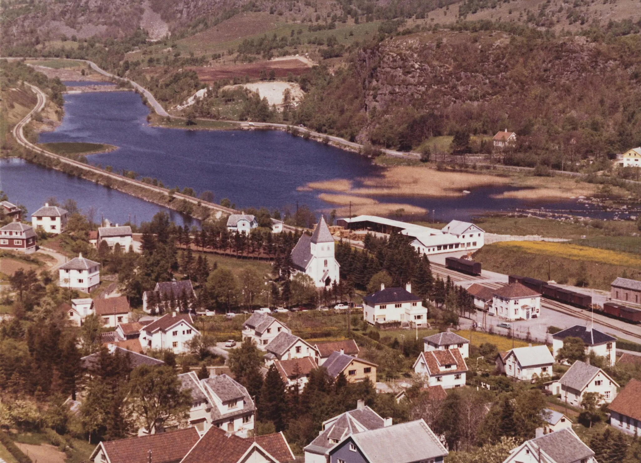 Photo showing: Flyfoto fra Ålgård i Gjesdal med blant annet stasjonen og gamlekirken. Widerøe-foto fra Nasjonalbibliotekets samling.