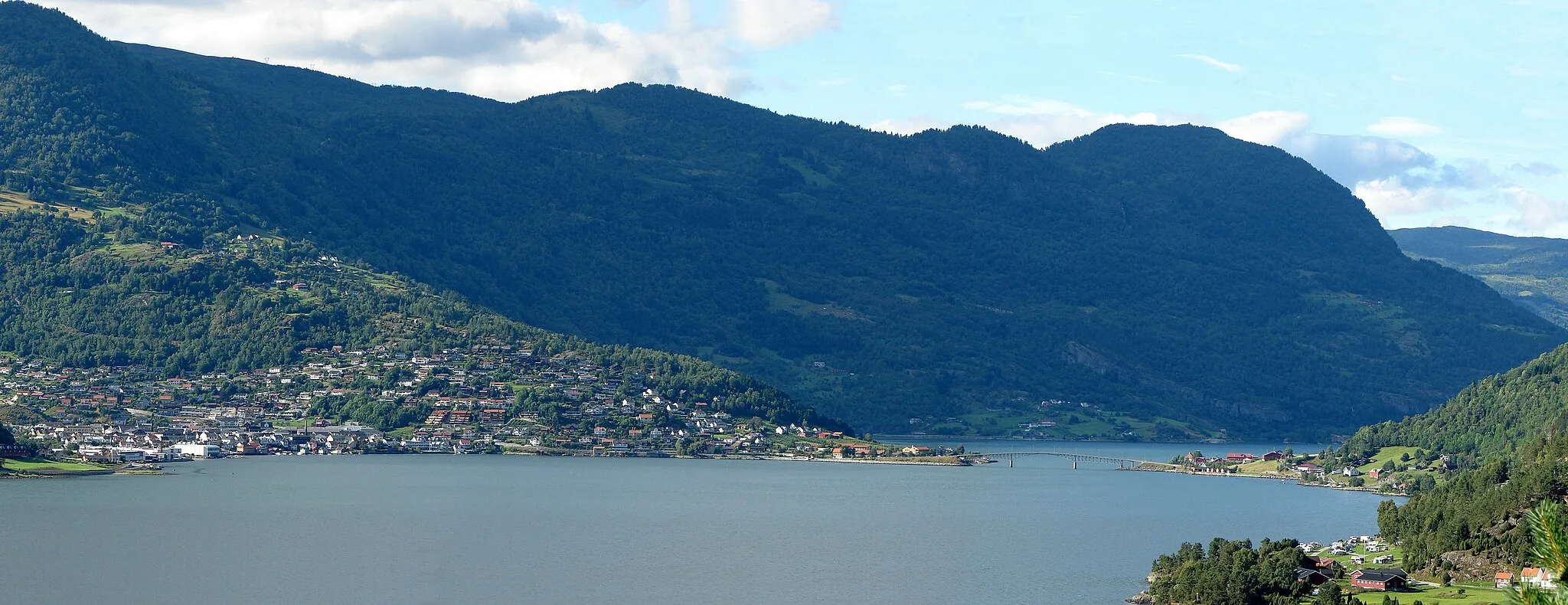 Photo showing: Sogndal and Loftesnes on the right side of the bridge.In front the Sogndals-fjord (arm of the Sognefjord)behind the bridge the Barsnes-fjord. There are 2 mainroads through Sogndal, Rv5 the bridge and RV55 left side of the Barsnesfjord  to the Sognefjell. Norwegian: Sogndal er kommunesenteret i Sogndal kommune og ligg inst i Sogndalsfjorden.RV55 og Rv5 har felles trasé gjennom Sogndal.