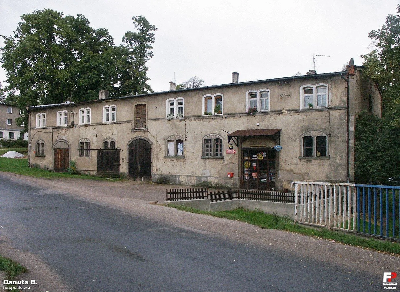 Photo showing: Dawny budynek inwentarski zaadaptowany na mieszkalny. Na parterze wygospodarowano lokal dla urzędu pocztowego. Zwracam uwagę na detal okien parteru.