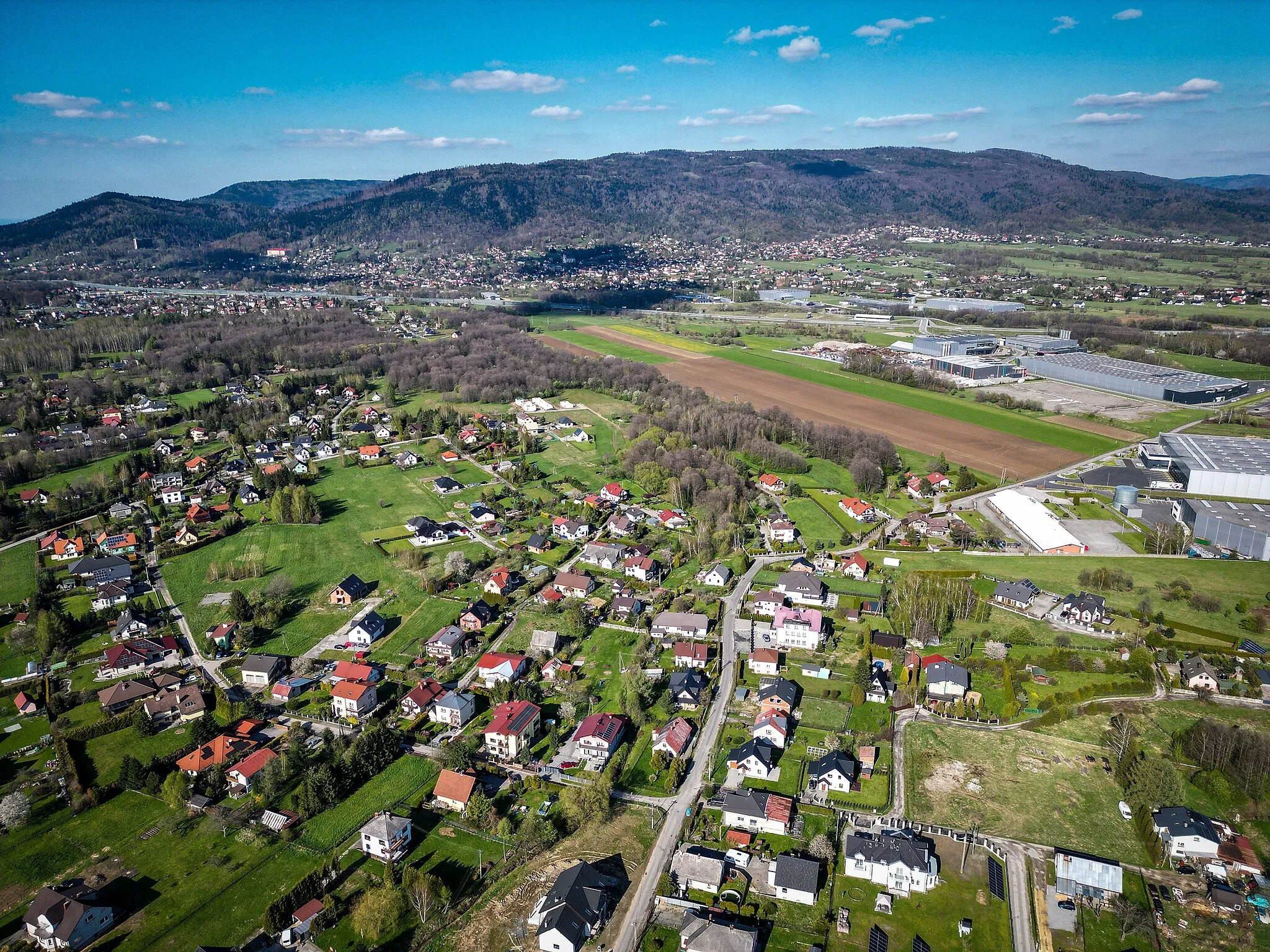 Photo showing: Meszna (silesian) aerial view of east boarder. At right part special economic zone in Wilkowice, in a background Wilkowice village and Magurka Wilkowicka mountain
