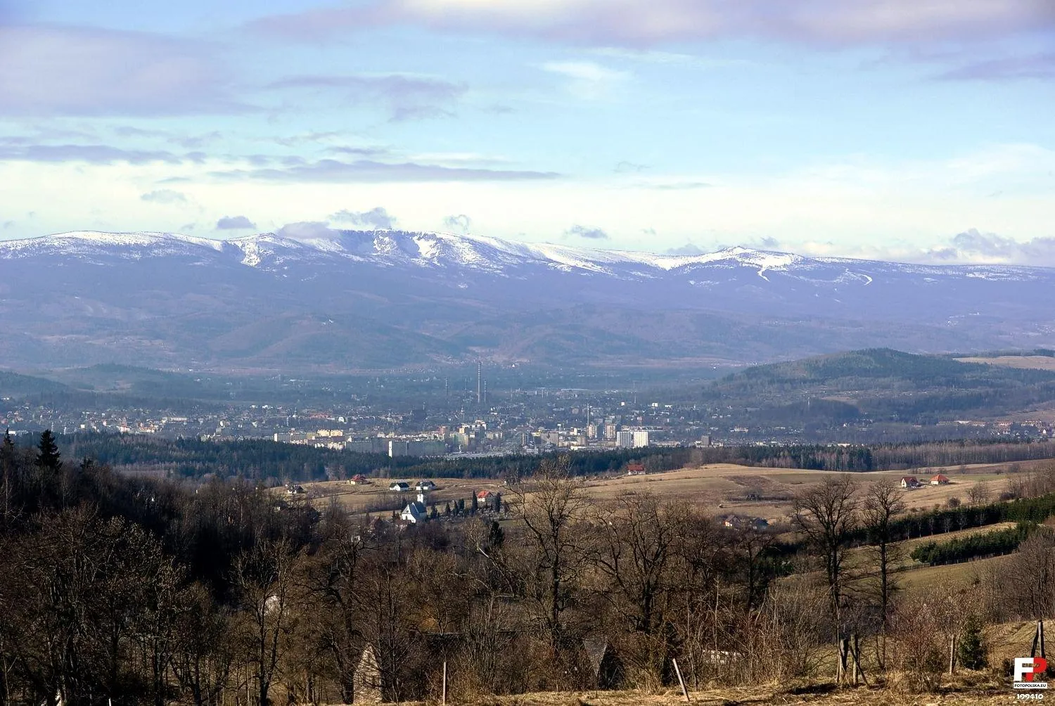 Photo showing: Panorama Karkonoszy od Czarnego Kotła Jagniątkowskiego aż do Szrenicy z białymi nartostradami. Bliżej widok na lekko zamgloną Jelenią Górę, a najbliżej widoczny po lewej stronie kościół w Dziwiszowie.