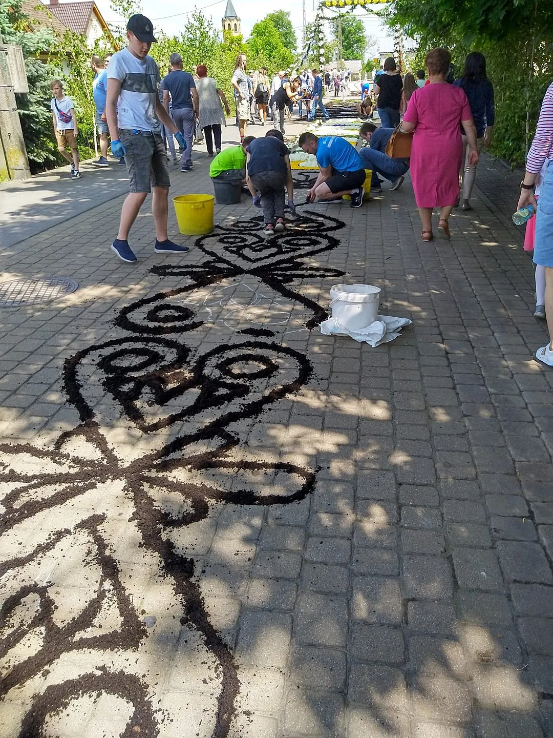 Photo showing: Every year at Corpus Christi, parishioners from Spycimierz in Poland lay a two-kilometer-long colorful carpet of living flowers. Before the flowers are arranged, the outlines of the pattern are created with black soil or white sand. On this day many visitors come here to admire the work of the inhabitants.
