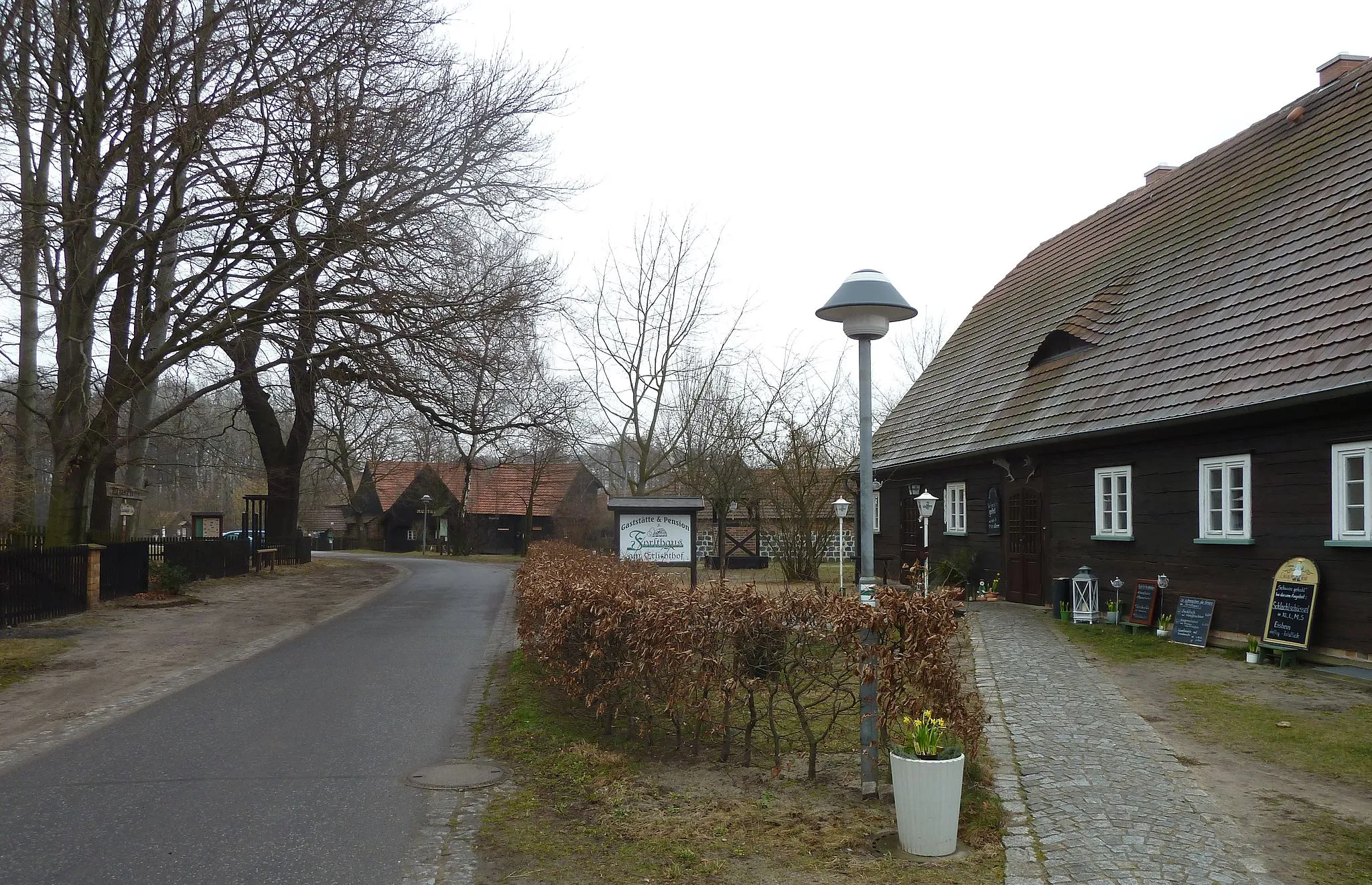 Photo showing: Die Erlichthofsiedlung in Rietschen: Forsthaus Altliebel Nr. 37, Glockenhäuschen mit der von Gerhard Schröder gestifteten Kanzlerglocke, im Hintergrund der namensgebende Erlichthof, vormals Mocholz Nr. 31.