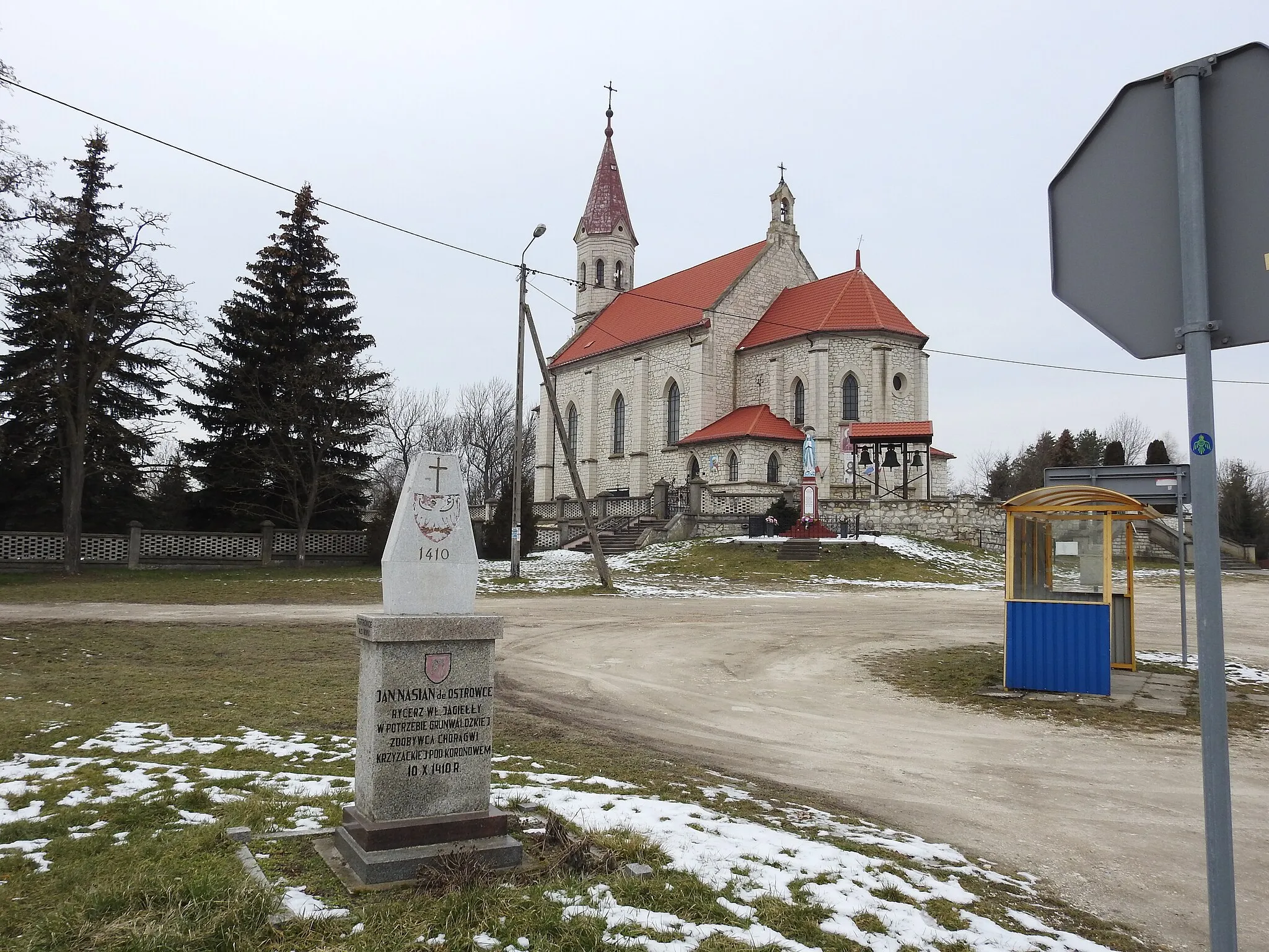 Photo showing: Ostrowce (village, Świętokrzyskie Voivodeship), February 11, 2023: St. John the Baptist and the obelisk of Jan Nasian de Ostrowce. View from the national road DK79