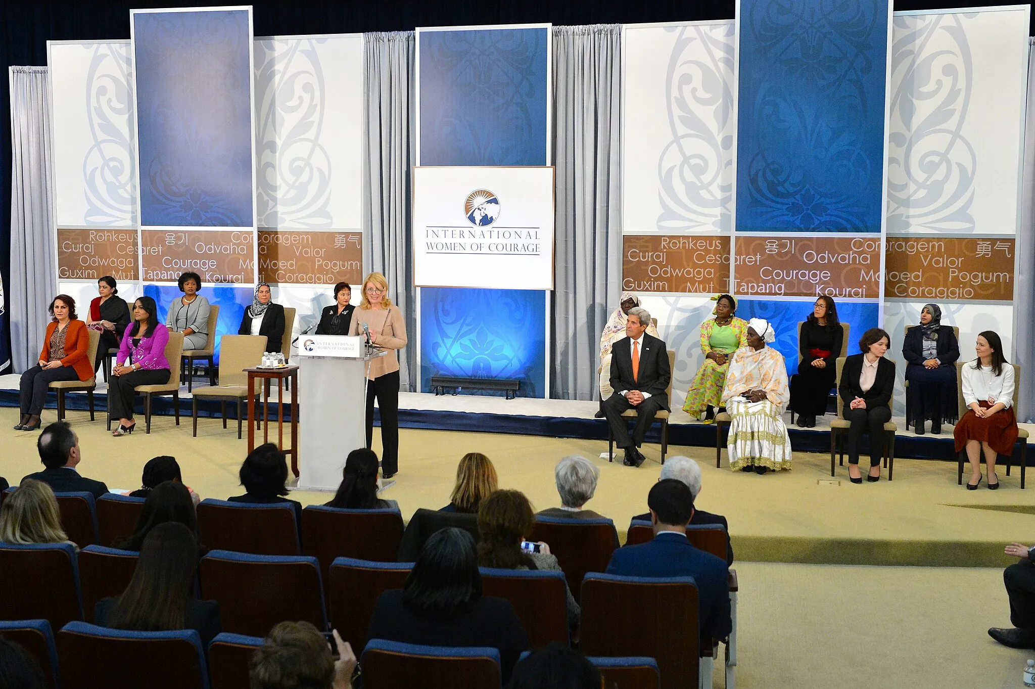 Photo showing: U.S. Ambassador-at-Large for Global Women's Issues Cathy Russell introduces U.S. Secretary of State John Kerry to speak at the 2016 Secretary of State’s International Women of Courage Award winners at the U.S. Department of State in Washington, D.C., on March 29, 2016. [State Department photo/ Public Domain]