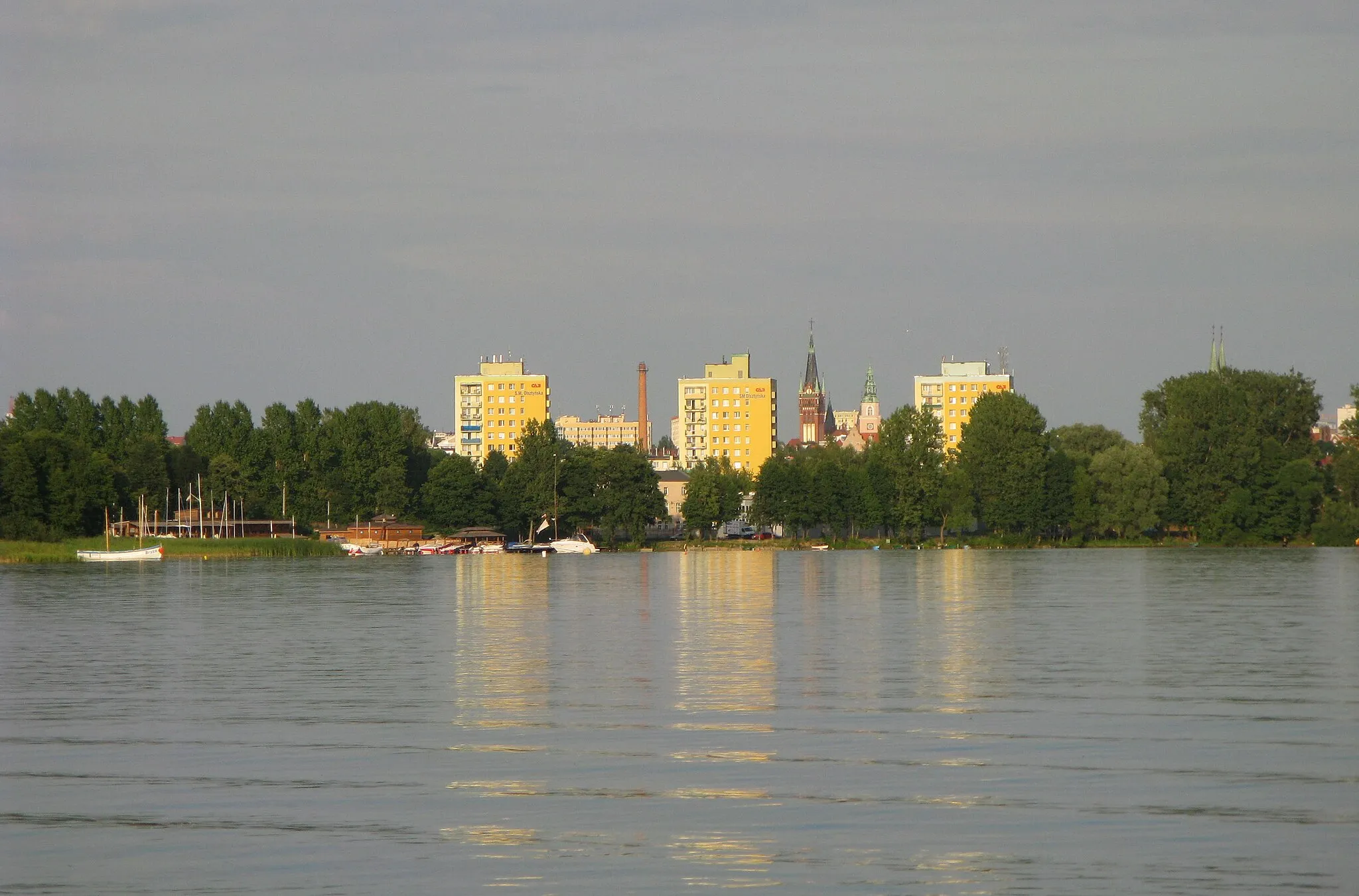 Photo showing: Widok Olsztyna z jeziora pl:Ukiel. Widoczny pl:Kościół Najświętszego Serca Pana Jezusa w Olsztynie oraz pl:Nowy Ratusz w Olsztynie