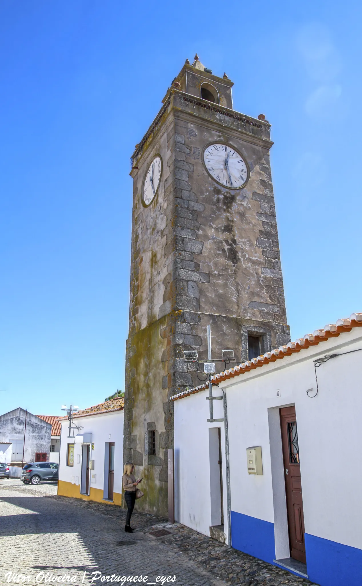 Photo showing: Dos monumentos profanos da Vidigueira, a Torre do Relógio é um dos que mais interesse merecem, não tanto pela torre em si, mas cuja data de construção ignoramos, pois não lhe encontramos qualquer referência que nos elucidasse, mas pelo sino que alberga, mandado fazer por Vasco da Gama em 1520, como consta da inscrição que nele se lê: Este sino mandou fazer o Sr. Conde Dom Vasco Almirante da Índia.
No decurso das obras de restauro foram colocados no relógio os ponteiros que este nunca tinha tido, de modo que os vidigueirenses possam não só ouvir o som familiar das suas badaladas, mas também saber as horas sempre que para lá olhem.

A torre é uma construção quadrangular, tendo no alto, para onde se sobe por uma escada de caracol, uma guarda com uma grilhagem em tijolos e um ornato em cada canto, e no meio, como remate, uma guarita ou coruchéu, que alberga o sino já referido e se abre para cada lado por um olhar com arco de volta inteira. www.freguesiavidigueira.pt/index.php/patrimonio/torre-do-...