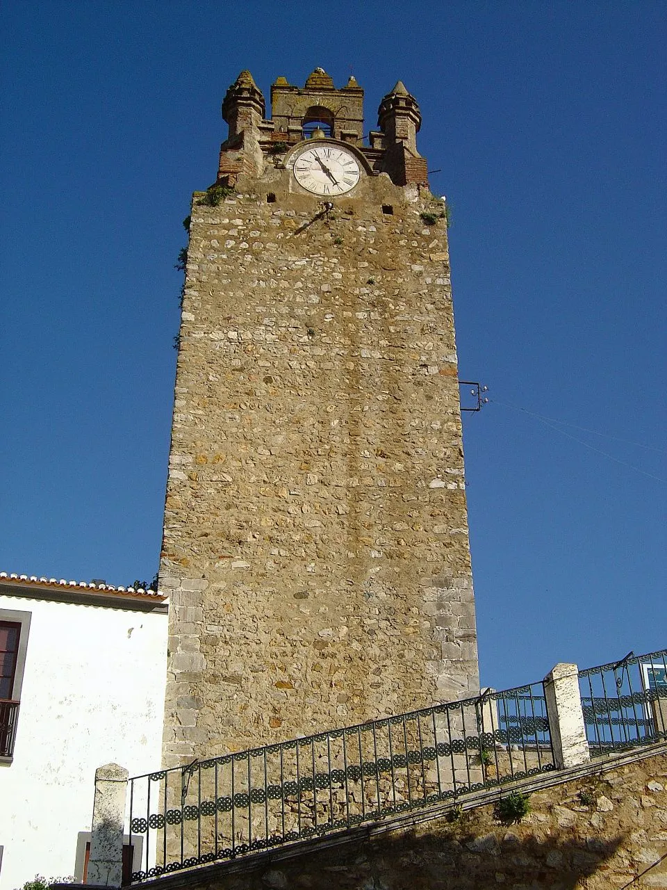 Photo showing: Dos pontos mais altos da Cidade é a sua majestosa Torre do Relógio. As ameias da parte mais alta da torre, terão caído ou sido derrubadas, no seu lugar foi construído por Mestre Pascoal, em 1440, o apoio onde assentam o relógio e o sino cujas badaladas marcam as horas e se ouve em toda a cidade.
Este apoio é feito de tijolo e não está em esquadria com a base da Torre.
A data acima referida é a que se encontra na inscrição existente por cima da porta de entrada da torre no Largo de Santa Maria que se transcreve:
«E : DE : MIL :
CCC :… XL : EM ...
XXXI …
DIAS: DE JANEIRO: …
E…UEEDOR: DESTA
OBRA … I …L …P... ASCOAL … MESTRE: …» Esta Torre situa-se ao cimo da escadaria monumental sita no largo D. Jorge de Melo que leva à Igreja Matriz de Santa Maria e ao Castelo Velho.
Possui no seu interior, uma escadaria em madeira com 52 degraus e no tecto de abóbada nervurada um escudo com quatro flores-de-lis.
O Relógio que sempre marcou a vida dos naturais da Vila, durante anos ficou parado e era uma tristeza para quem se habituou a ouvi-lo.
Em boa hora a Câmara Municipal o mandou reparar e hoje pode ouvir-se de novo, na agora Cidade de Serpa as "badaladas" que marcam o tempo. serpa-eriovasti.blogspot.com/2006/08/torre-do-relgio_15.html

See where this picture was taken. [?]