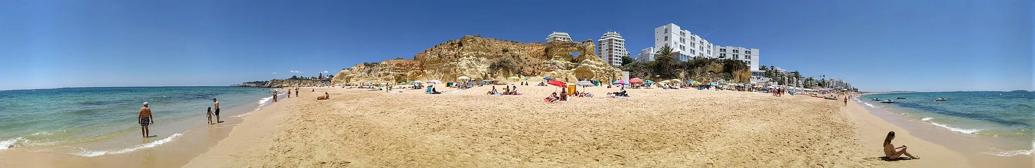 Photo showing: Panoramic view of Praia de Armação de Pêra from the surf, showing the Holiday Inn, cliffs, and more