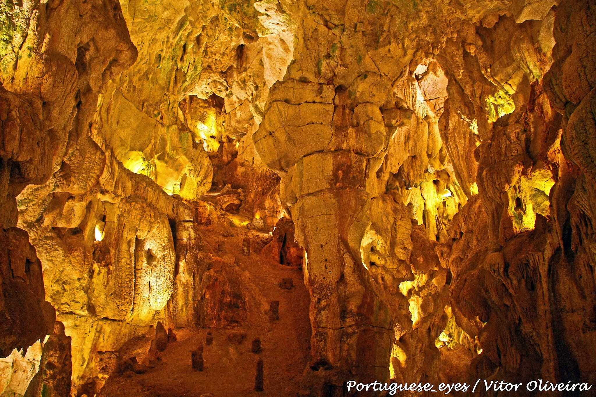 Photo showing: As grutas foram descobertas em 1971 por dois caçadores que andavam a perseguir uma raposa. A curiosidade levou-os a explorar o algar em toda a sua extensão, logo uma sala - a "Sala do Pastor", repleta de formações calcáreas. Durante perto de dois meses, os dois homens continuaram a escavar as estreitas fendas que se seguiram à primeira caverna, desvendando pouco a pouco as demais salas e galerias que hoje se incluem no percurso visitável.
Entretanto foram contratados geólogos e outros técnicos e procedeu-se ao aproveitamento da gruta como atração turística preservando-se rigorosamente as suas características incluindo a paisagem serrana da superfície.
Características
A beleza da gruta é assegurada pela diversidade de materiais argilosos e de calcites. Os nomes das salas sugerem as imagens que cada uma evoca ao visitante: "Presépio", "Pastor", "Cascata", "Virgem", "Cúpula Vermelha", "Marítima", "Capela Imperfeita", "Bolo de Noiva", "Abóbada Vermelha" e "Fonte das Lágrimas".
A extensão visitável da gruta é de 350 metros, atingindo-se uma profundidade de 45 metros. A temperatuira interior da gruta é, em média, de 18 graus Celsius.
A entrada e saída da gruta é feita em locais diferentes, envolvidos por uma característica paisagem serrana.
Lenda da Gruta
Segundo a tradição local, um homem abastado das redondezas, ao passar por um matagal em torno de um covão, foi atacado e saqueado por um bando de malfeitores que o assassinaram, como era frequente em tempos idos. O corpo sem vida foi atirado para o precipício cavernoso e, na pressa, os assaltantes deixaram cair, com o corpo da vítima, o saco das moedas que esta transportava e cujo roubo fora o móvel do crime. As moedas se espalharam pelo precipício, perdendo-se irremediávelmente, o que deu ao algar o nome pelo qual ainda hoje é conhecido. pt.wikipedia.org/wiki/Grutas_da_Moeda

See where this picture was taken. [?]